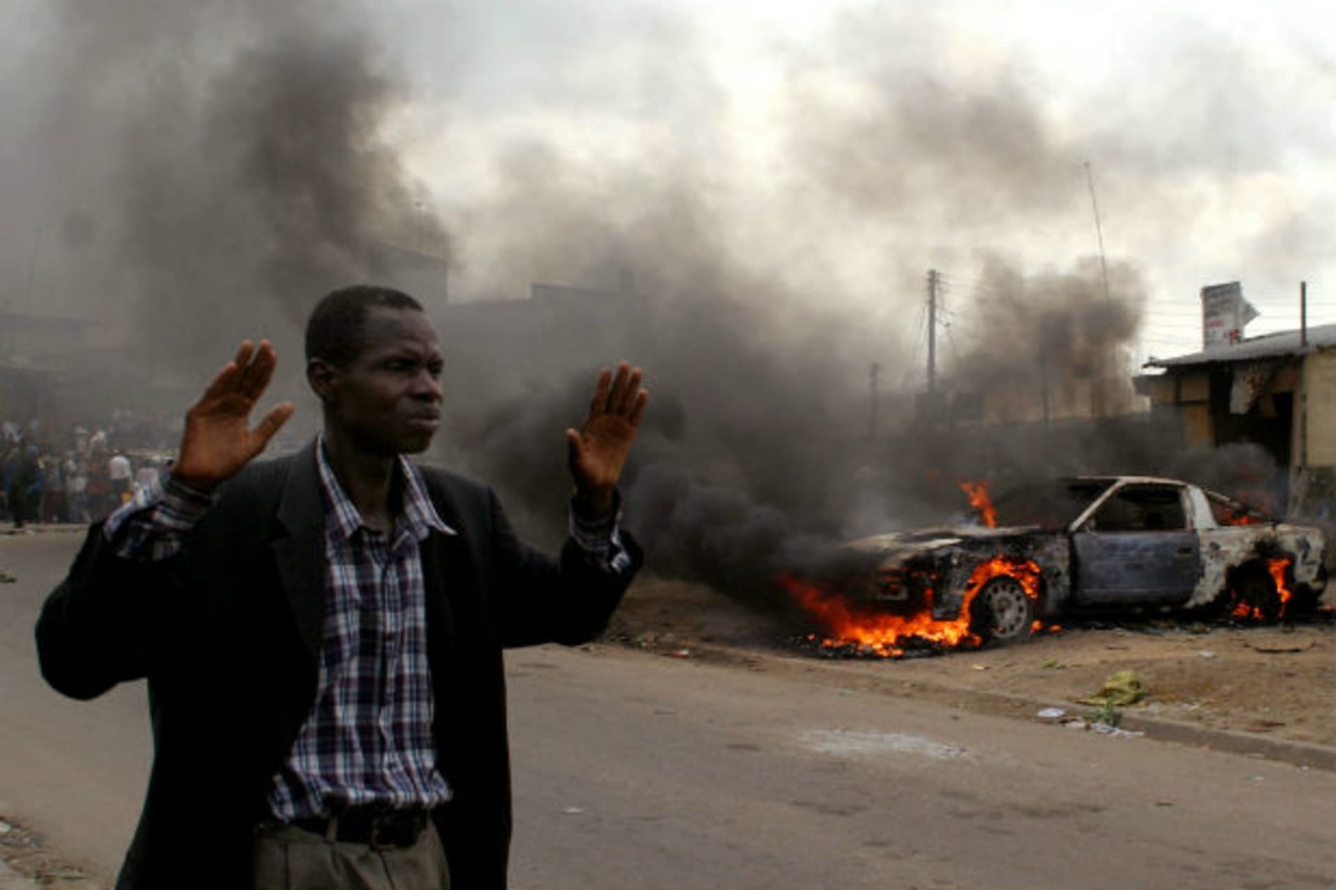 A man walks past a burning car in Oshodi, Lagos south west Nigeria May 24, 2005.