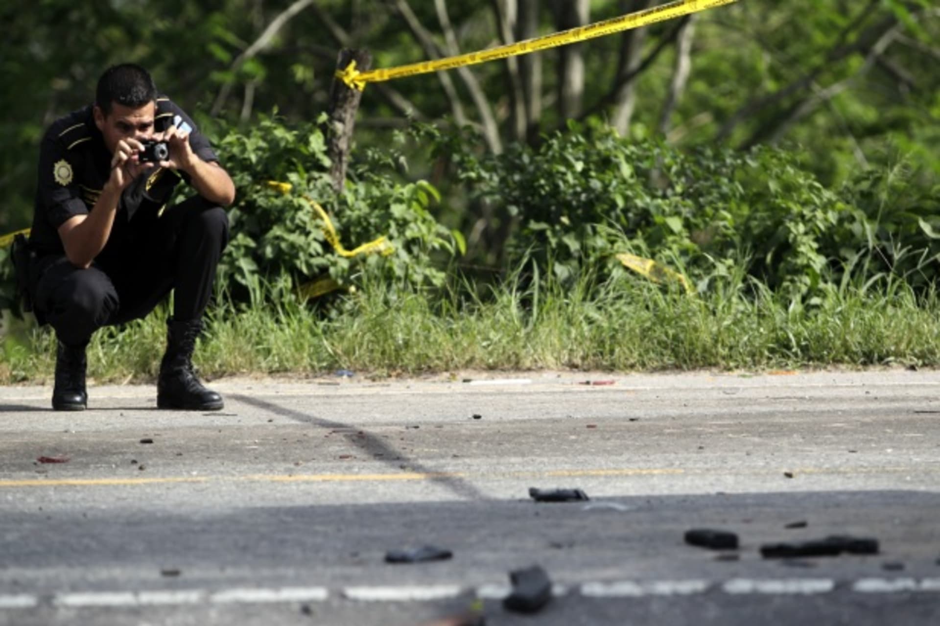 <p>A policeman takes photos at the scene of a deadly shootout near Zacapa, Guatemala (Courtesy Reuters/Daniel Leclair).</p>
