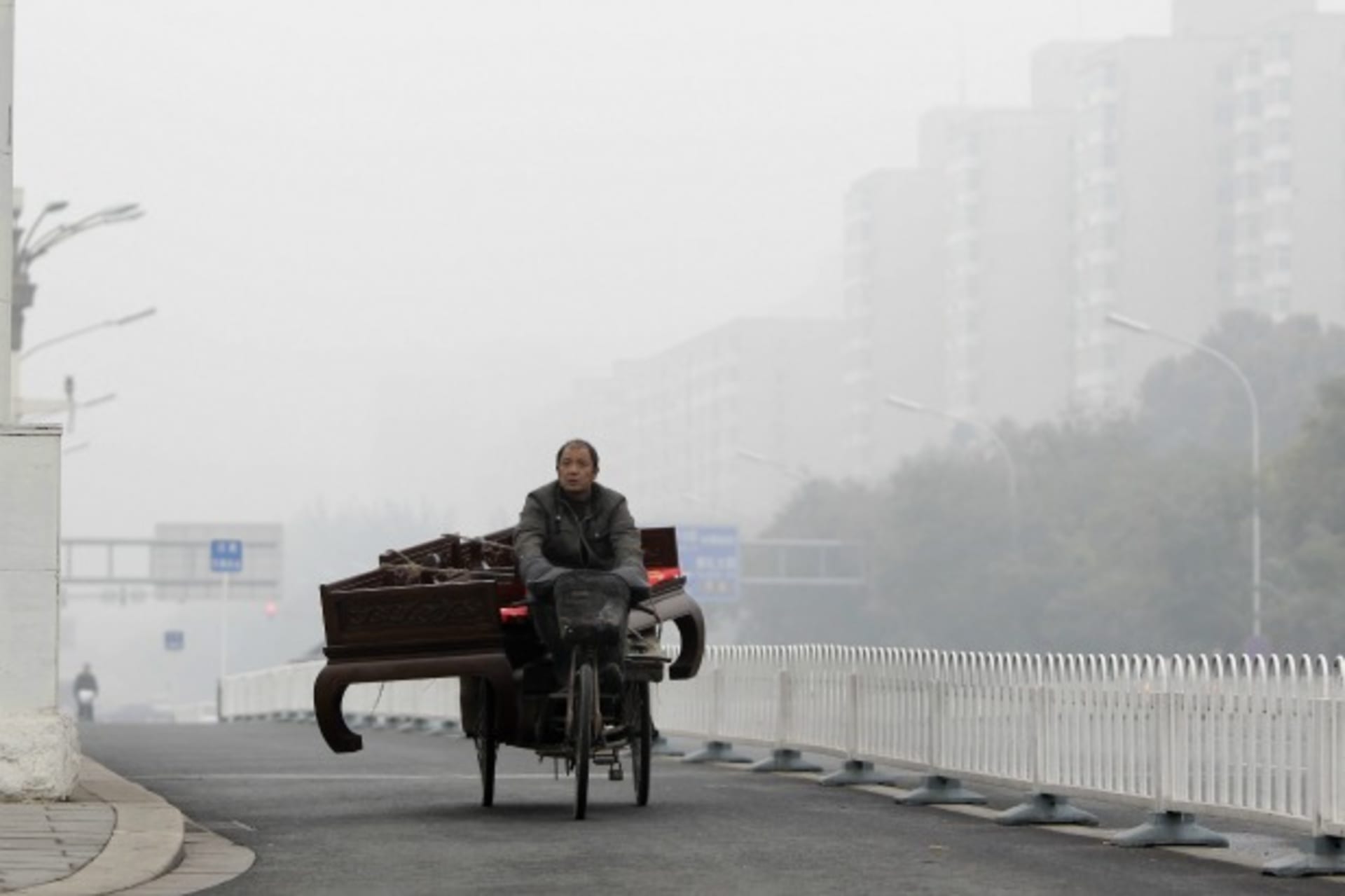 <p>A man rides a tricycle carrying a couch on a road amid heavy smog in central Beijing on October 31, 2011.</p>

