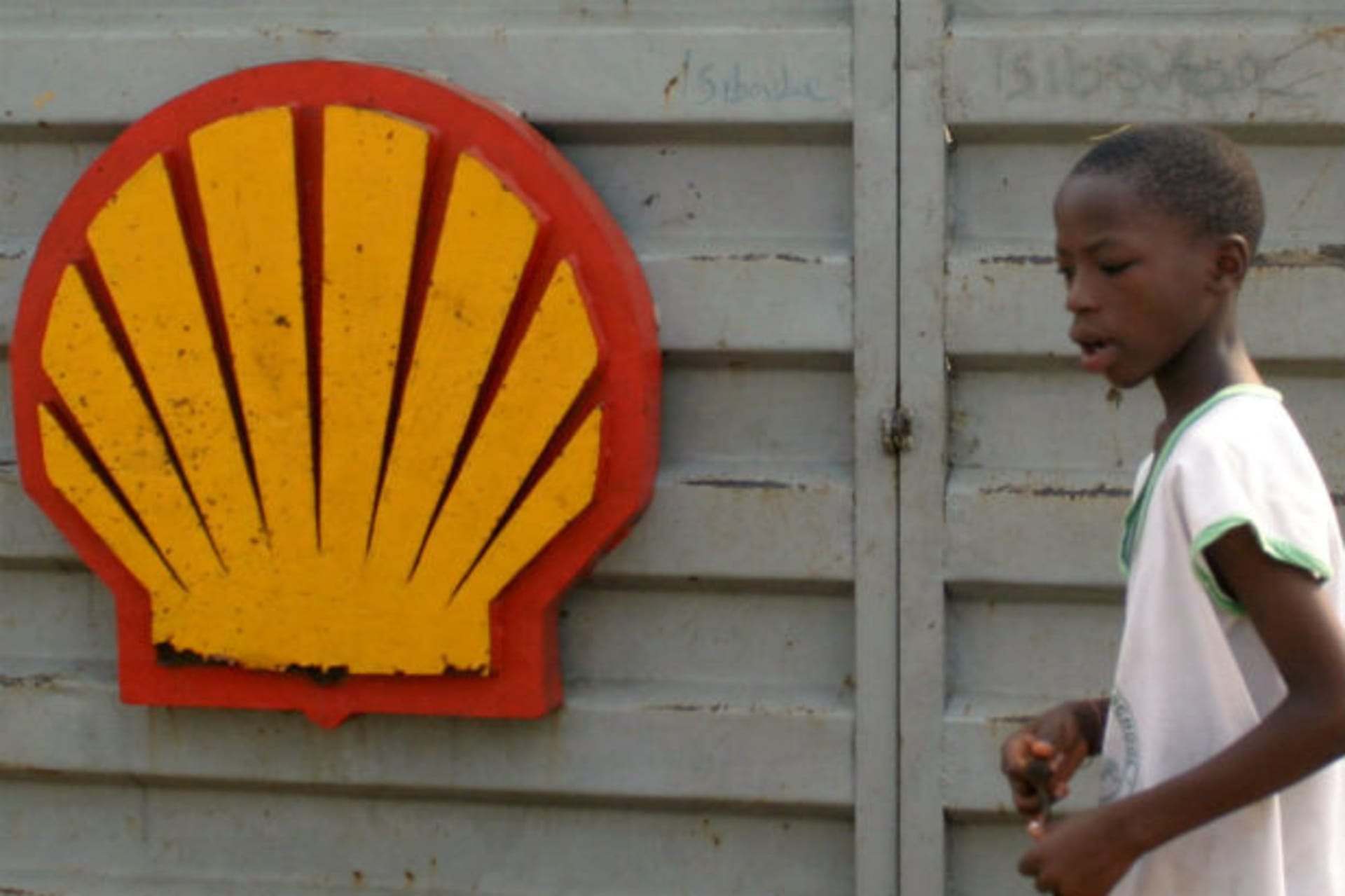A Nigerian schoolboy walks past the logo of Dutch oil giant Shell near Warri in the volatile Niger-Delta region January 17,2006.