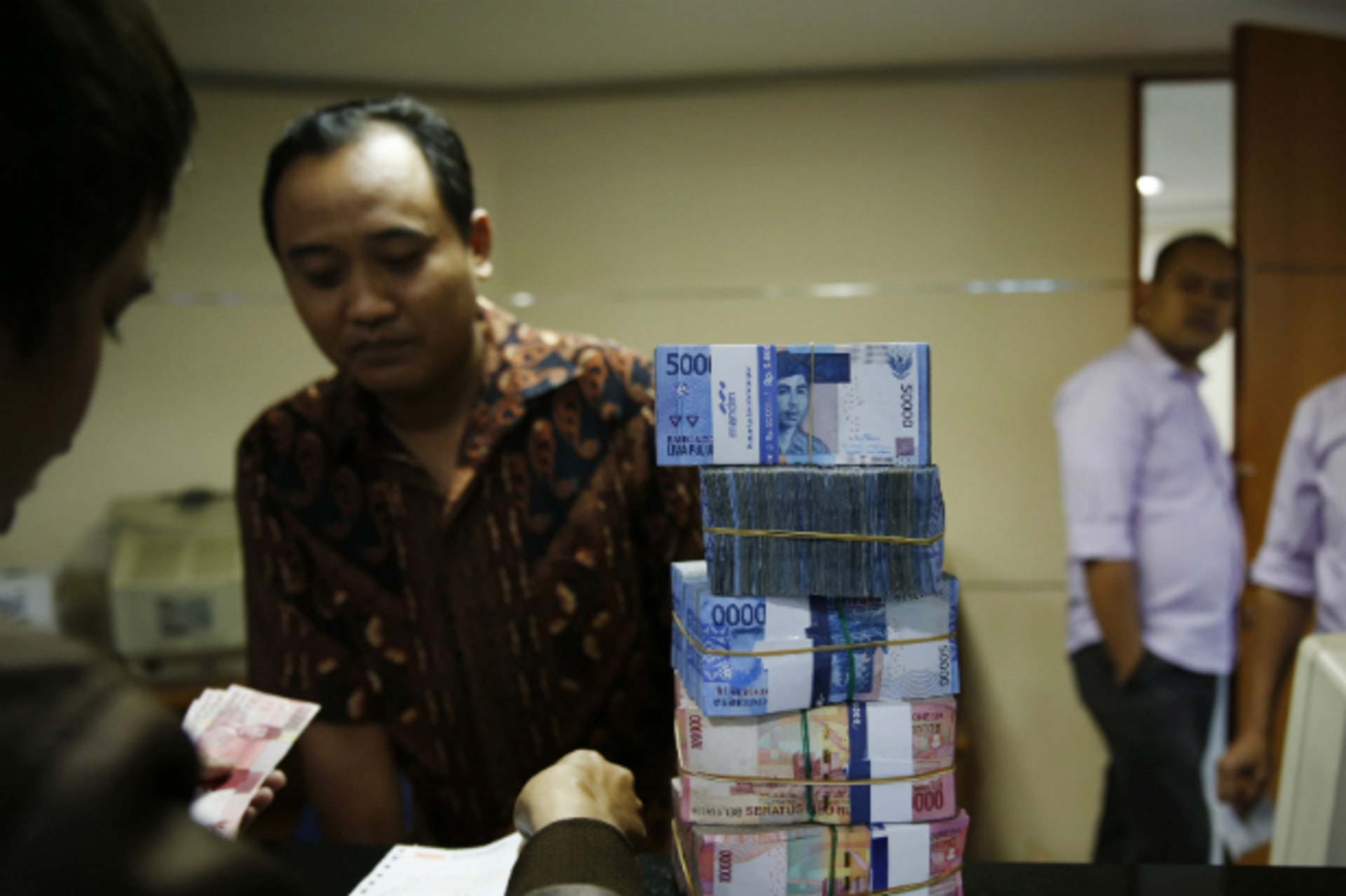 <p>A money changer (facing camera) helps a customer convert Indonesian rupiah in Jakarta on August 20, 2013. Asian emerging market currencies extended losses on Tuesday, with the rupiah hitting a fresh four year low. (Beawiharta Beawiharta/Courtesy Reuters)</p>

