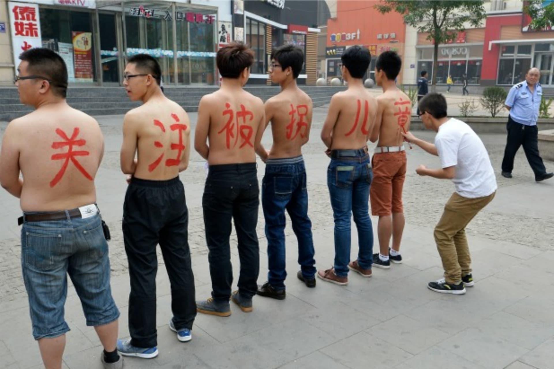 <p>A security guard (R) looks on as a man writes characters on the back of six topless activists with the message “pay attention …hildren abduction and trafficking, in Taiyuan, Shanxi province May 18, 2013. REUTERS/Jon Woo (CHINA – Tags: CRIME LAW SOCIETY)</p>
