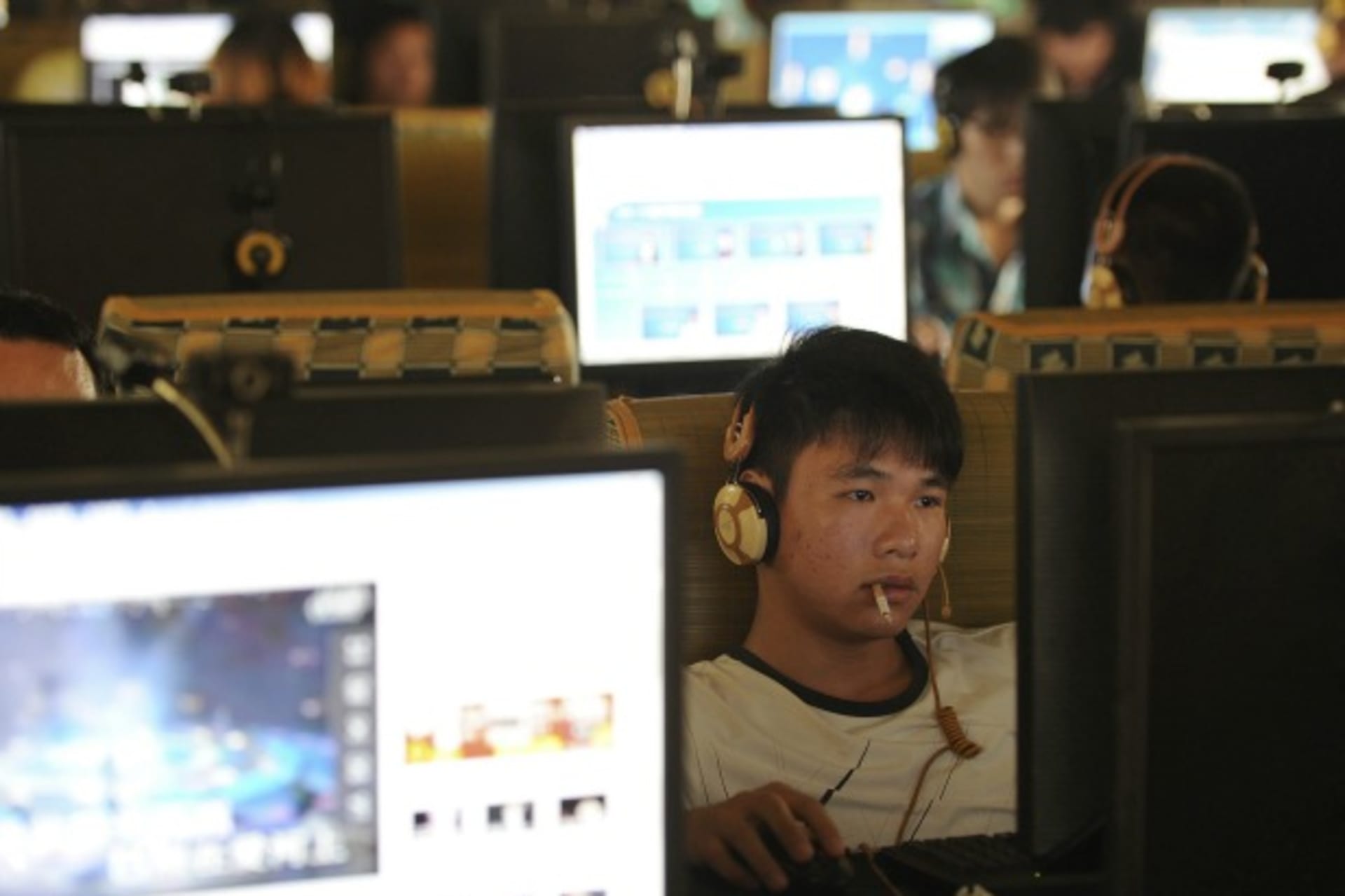 <p>A man smokes as he uses a computer at an internet cafe in Hefei, Anhui province,</p>
