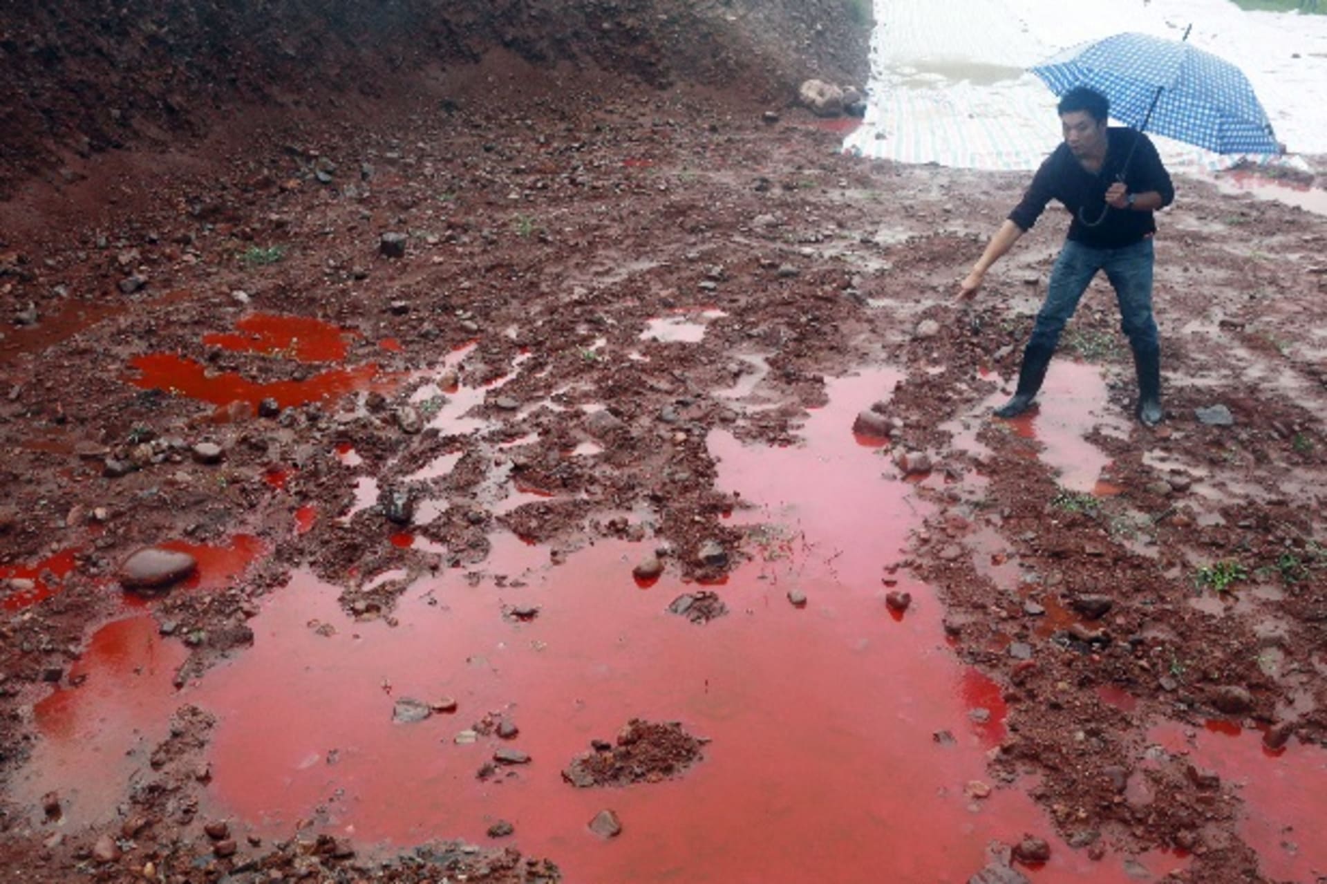 <p>A man points to water and soil which turned red after being contaminated by industrial waste from a closed dye factory, amid h…r an explosion which caused dye leakage and polluted the underground water. Picture taken September 15, 2014. REUTERS/Stringer</p>
