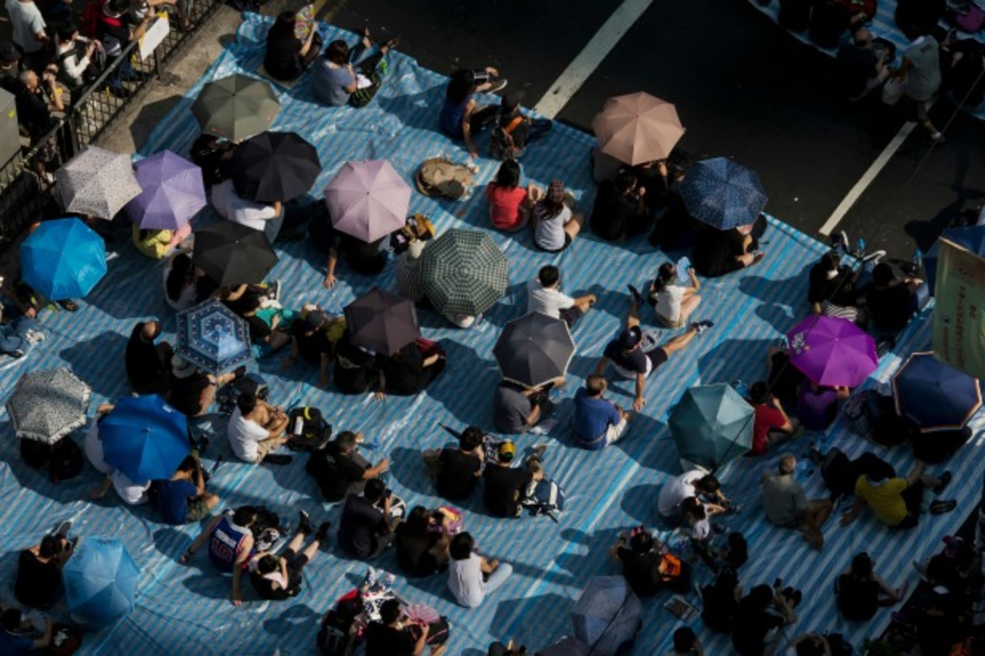 <p>Protesters sit under umbrellas at a main street at Mongkok shopping district after thousand of protesters blocked the road in Hong Kong on October 1, 2014. (Tyrone Siu/Courtesy Reuters)</p>
