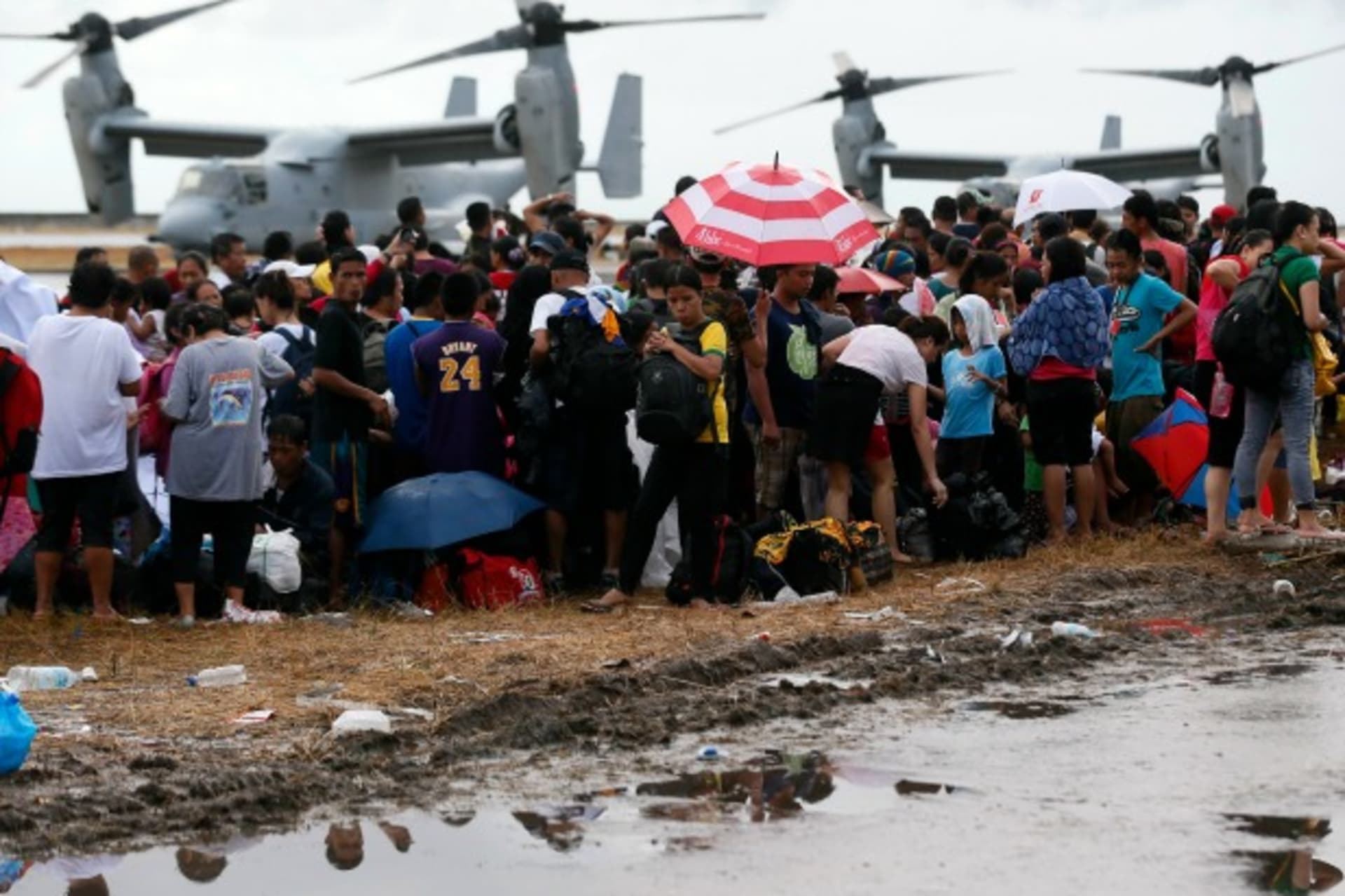 <p>People wait to be airlifted to Manila as Ospreys from the U.S. Navy Ship (USNS) Charles Drew taxi on the tarmac in the background, at Tacloban airport on November 14, 2013 (Wolfgang Rattay/Courtesy Reuters).</p>
