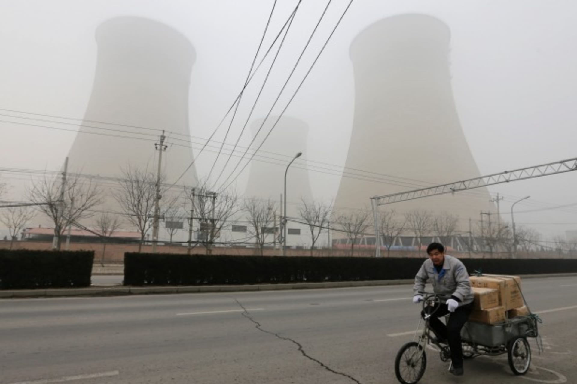 <p>A man cycles past the water-cooling towers of a coal-fired power plant on a hazy day in Beijing on January 22, 2013. (Jason Lee/Courtesy Reuters)</p>
