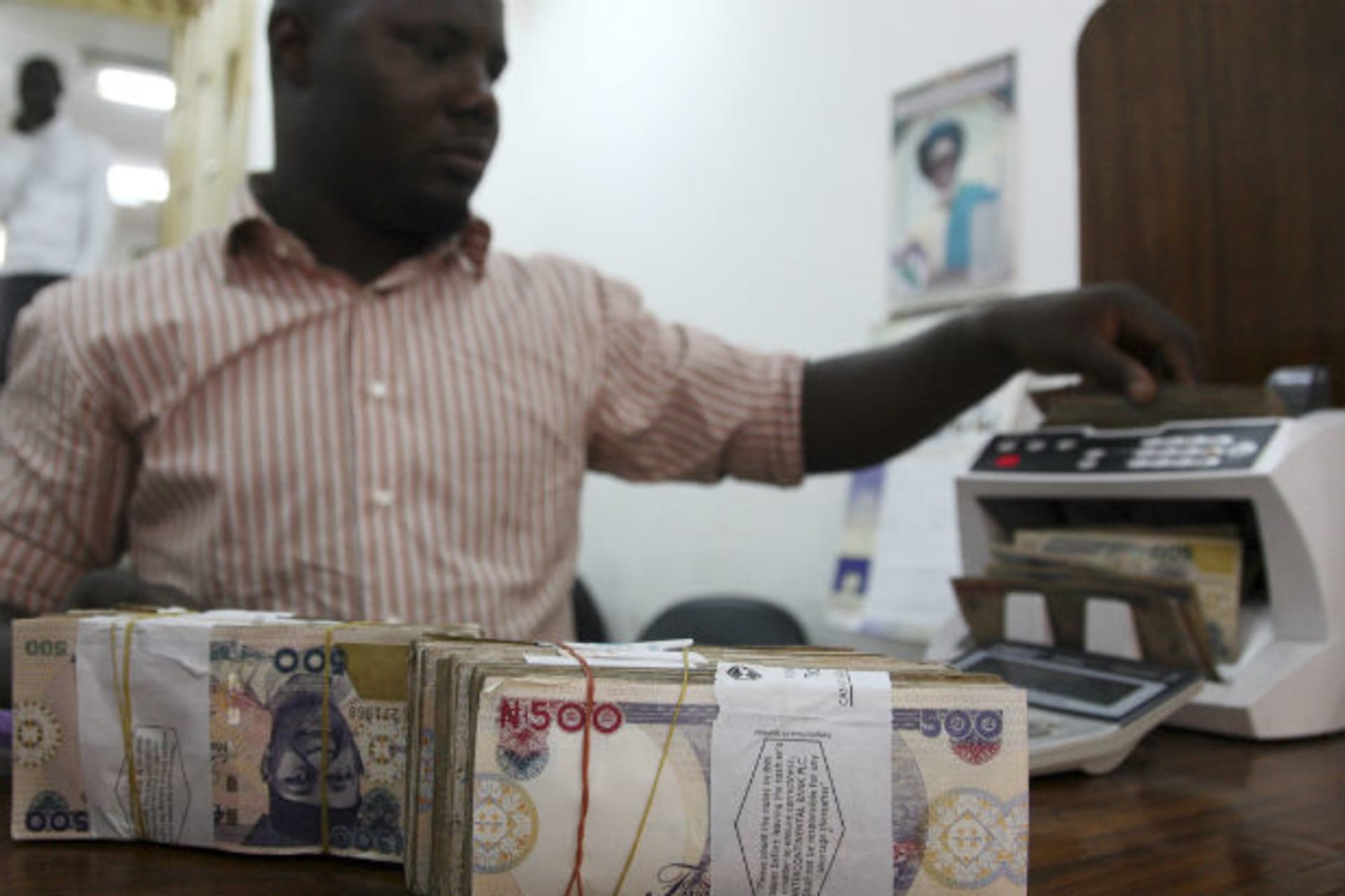 A money dealer counts the Nigerian naira on a machine in his office in the commercial capital of Lagos, January 13, 2009.
