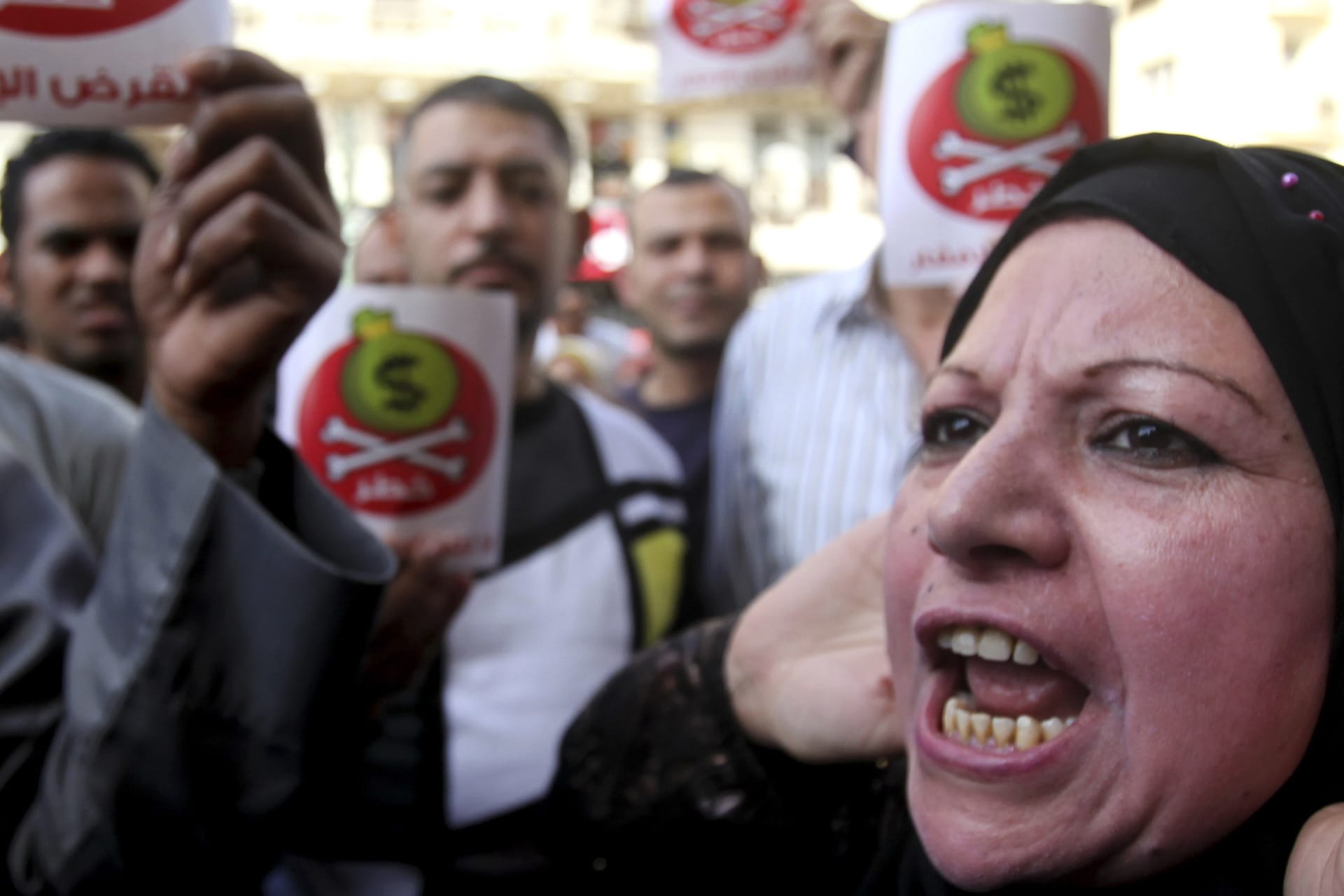 <p>Egyptian protesters hold placards with the Arabic inscription reading ‘danger’ and shout slogans as they demonstrate against the International Monetary Fund (IMF) delegation visit, in front of the General-Prosecutor’s office in Cairo on April 3, 2013.</p>
