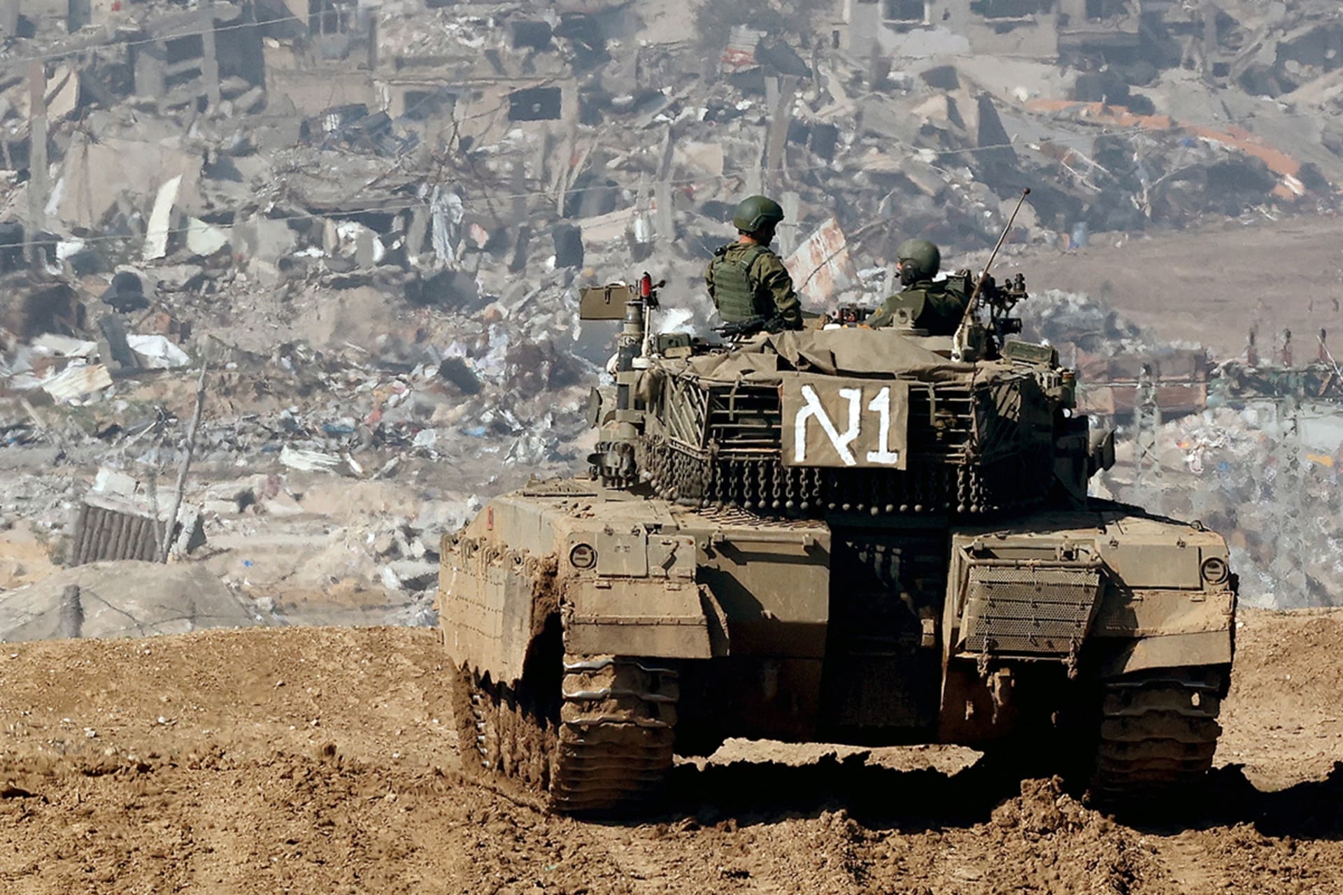 <p>An Israeli tank drives past damaged buildings near the Gaza Strip border in southern Israel on January 19, 2024.</p>
