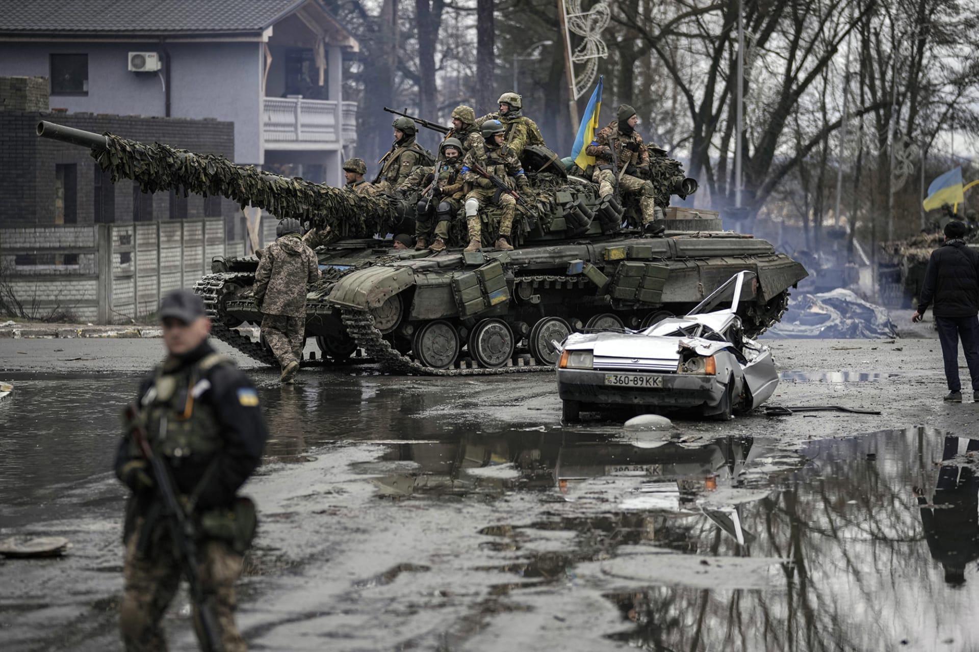 <p>Ukrainian servicemen ride a tank next to a civilian vehicle destroyed during fighting between Russian and Ukrainian forces outside Kyiv, Ukraine, on April 2, 2022.</p>

