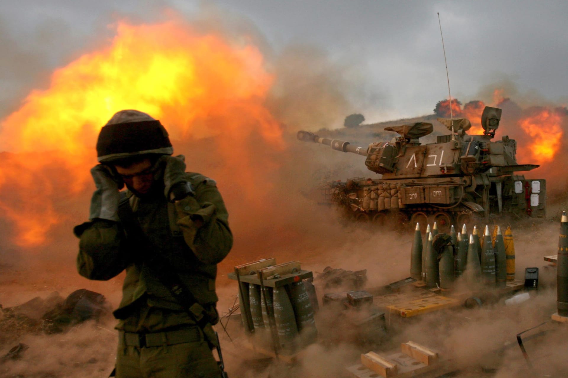 <p>An Israeli soldier stands near a mobile artillery unit as it fires a shell into southern Lebanon from its position in Zaura, northern Israel, on July 13, 2006</p>
