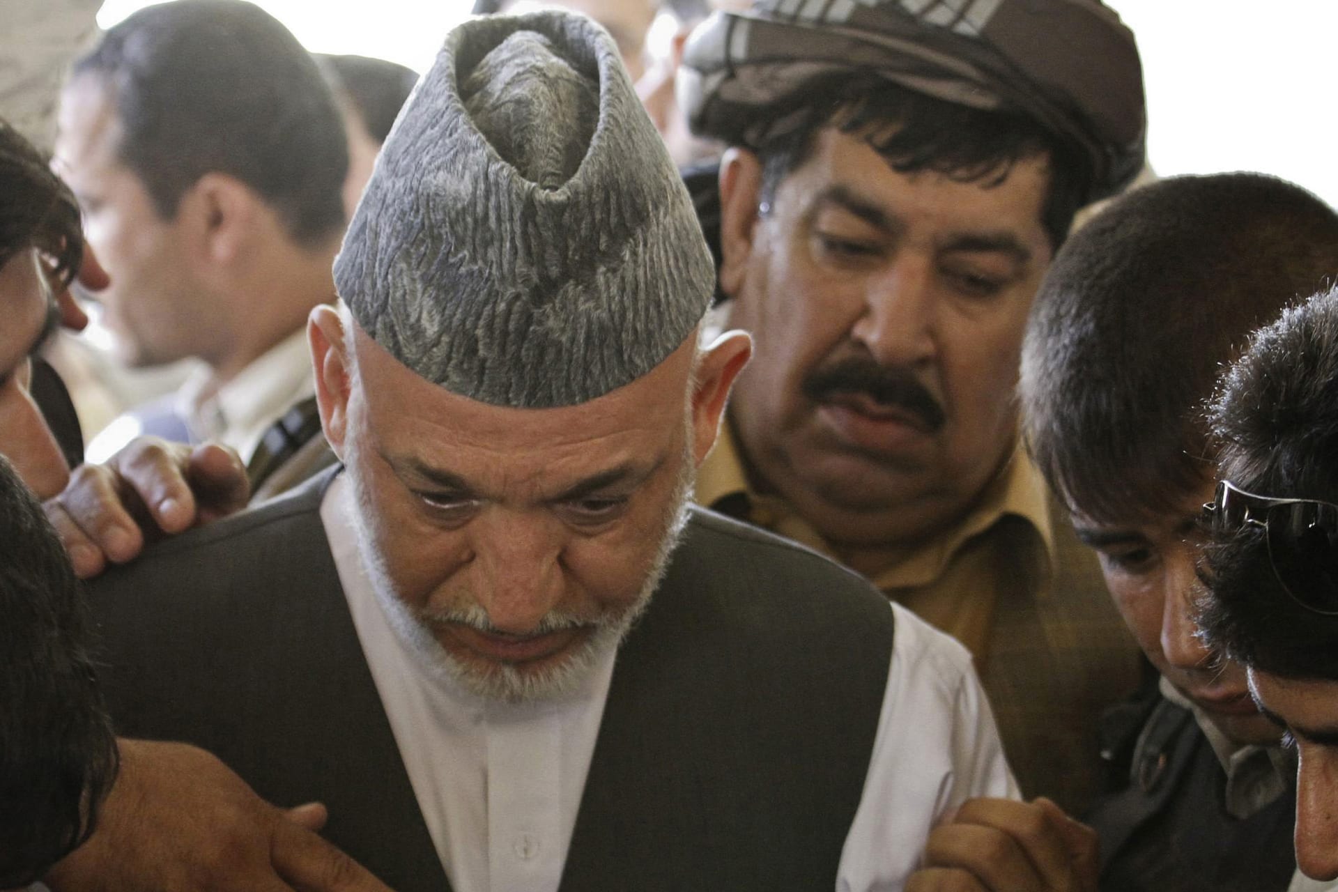 <p>Afghan President Hamid Karzai looks down at the grave of his brother Ahmad Wali Karzai during his burial ceremony in Kandahar province on July 13, 2011.</p>
