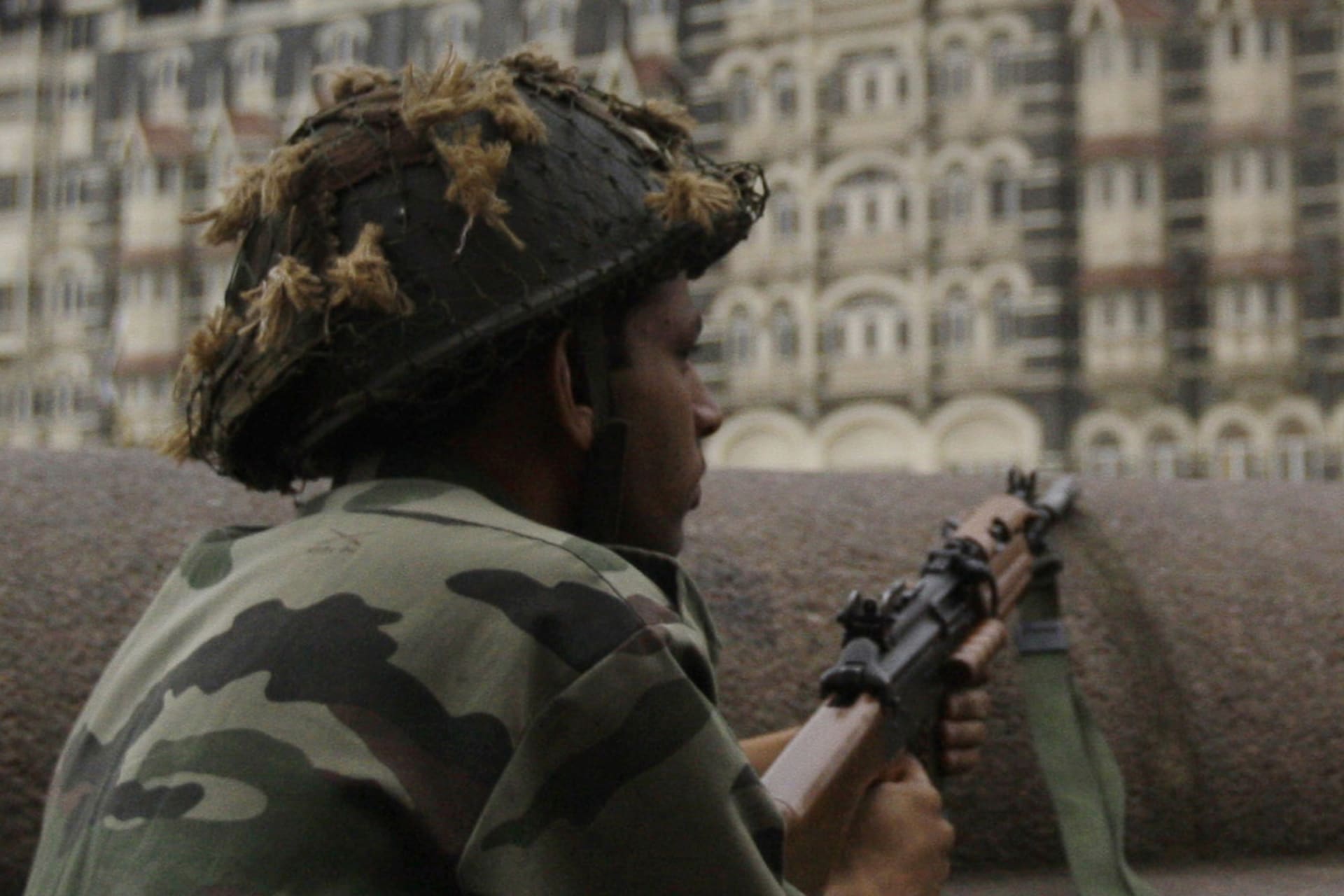 <p>The Taj Hotel burns as Indian soldiers take cover along a sea wall during gun battles between Indian troops and militants in Mumbai on November 29, 2008.</p>
