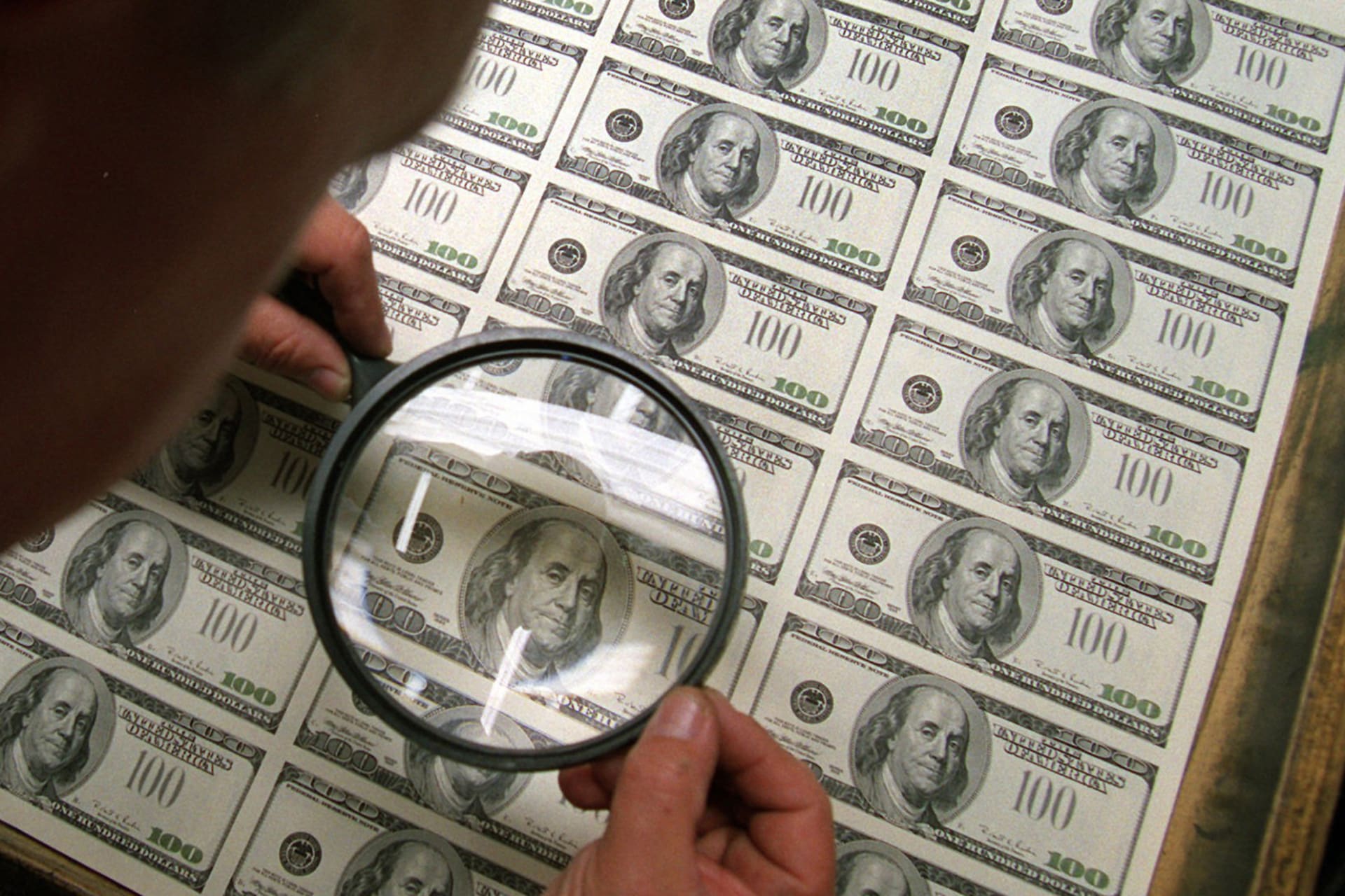 <p>A Bureau of Engraving and Printing employee uses a magnifying glass to inspect fresh newly designed $100 bills on March 21, 1996, at the agency in Washington.</p>
