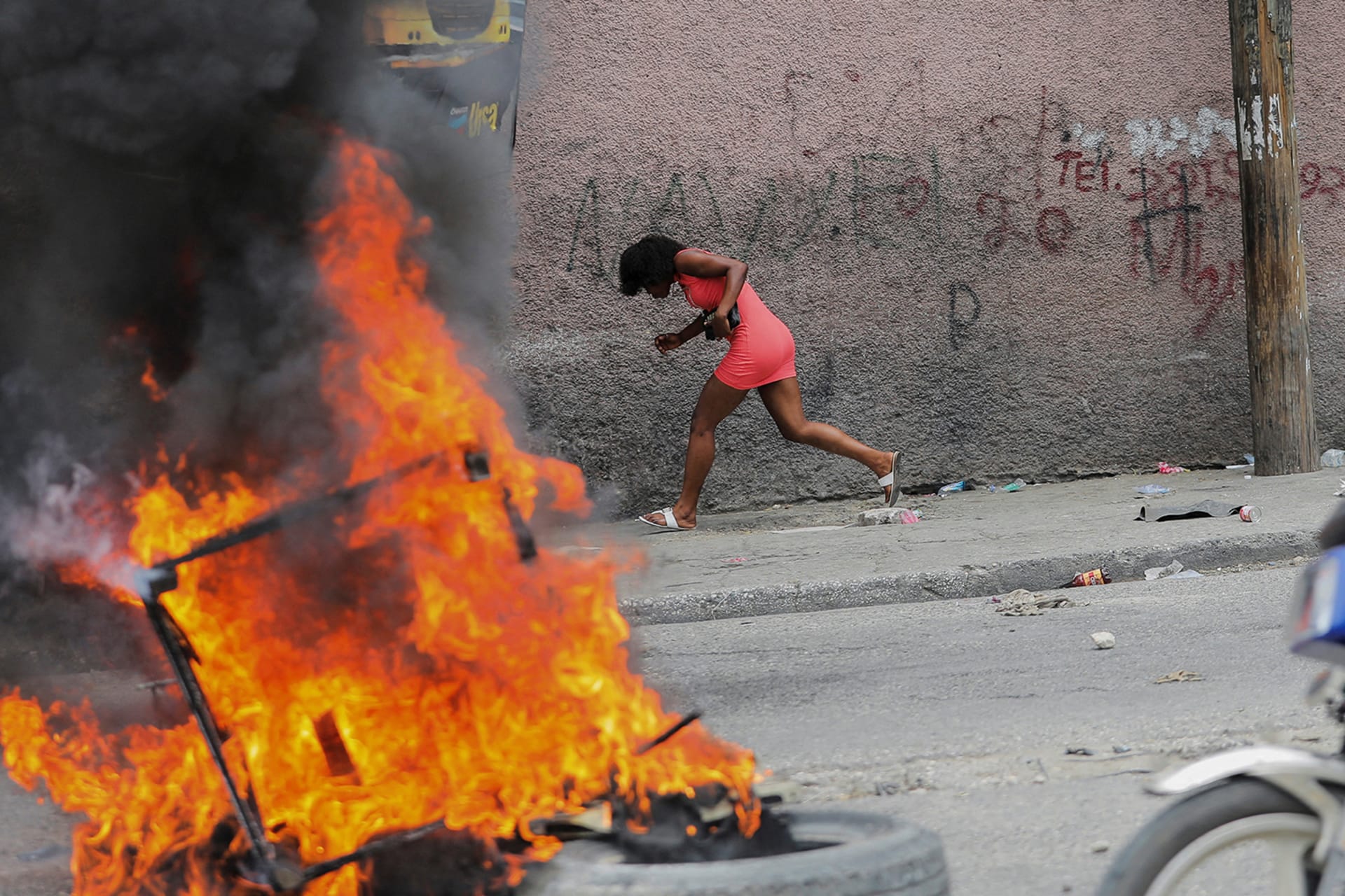 <p>A woman runs past a burning barricade during a protest against growing fuel scarcity, soaring consumer prices, and crime in Port-au-Prince, Haiti, on August 29, 2022.</p>
