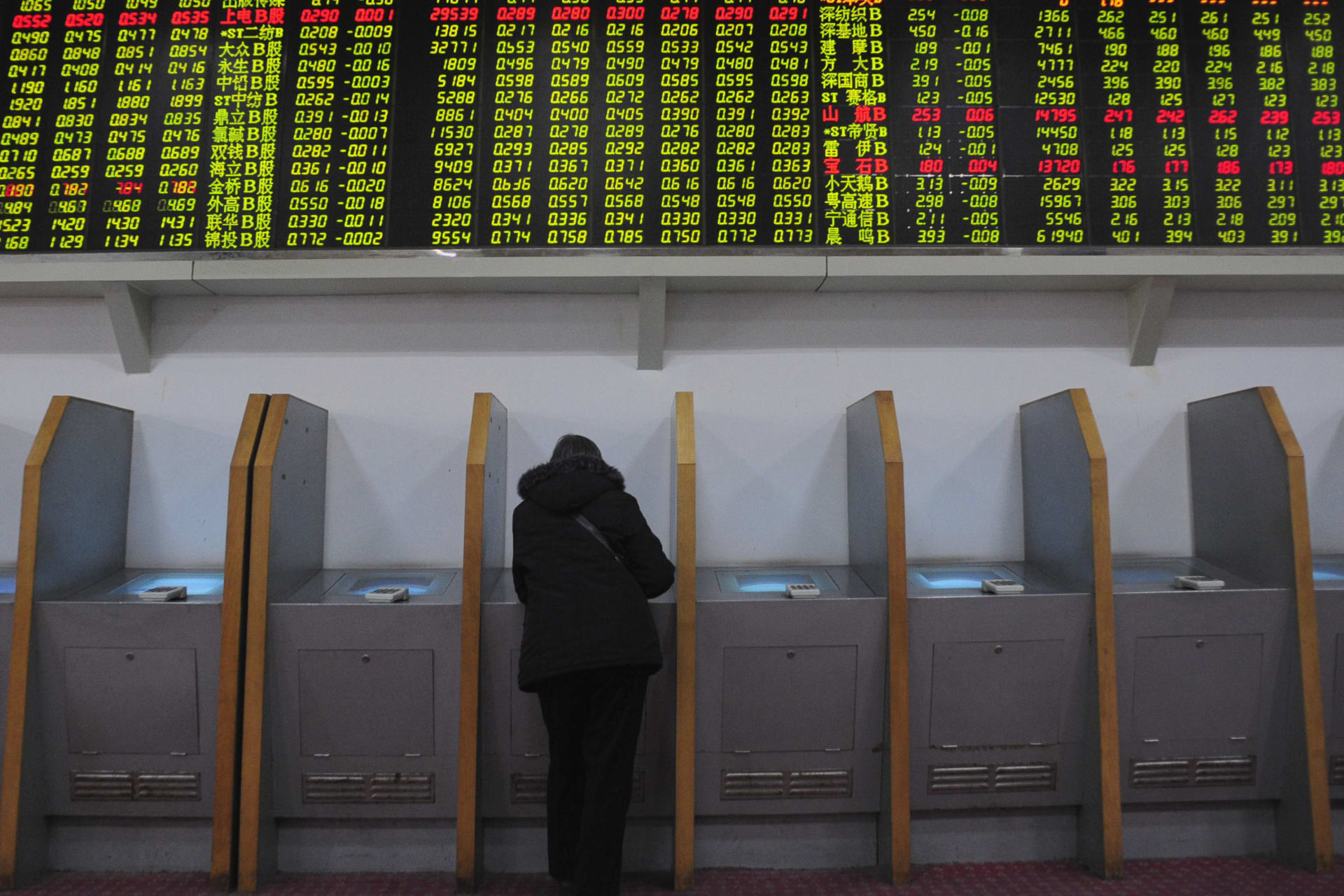 <p>An investor trades stocks under a screen showing stock information at a brokerage house in Hefei, Anhui province on February 18, 2009.</p>
