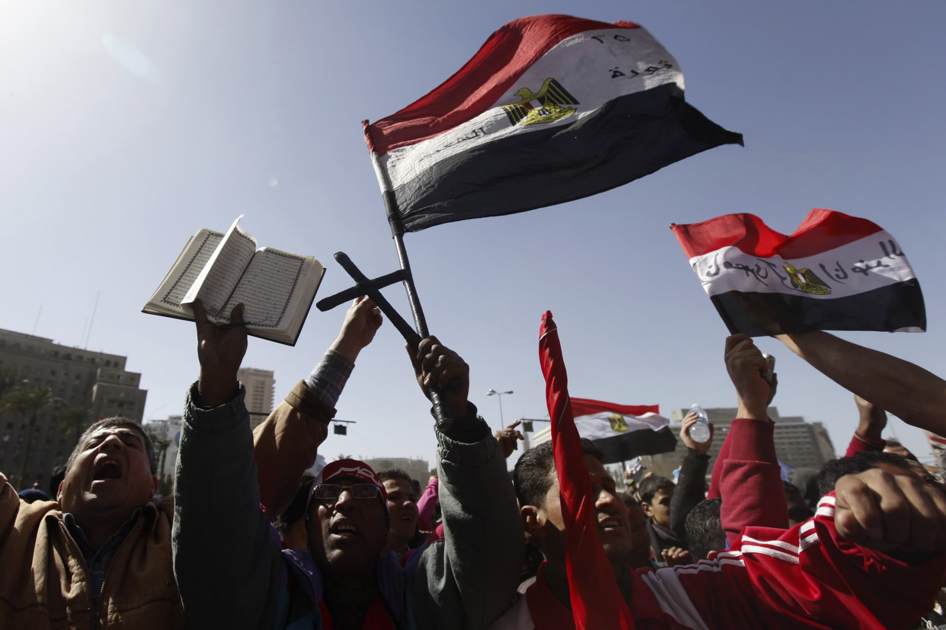<p>A protester, who opposes Egyptian President Mohamed Mursi, holds a cross, a Koran and a national flag as he shouts slogans during a demonstration against Mursi and members of the Muslim Brotherhood at Tahrir Square in Cairo on February 15, 2013.</p>
