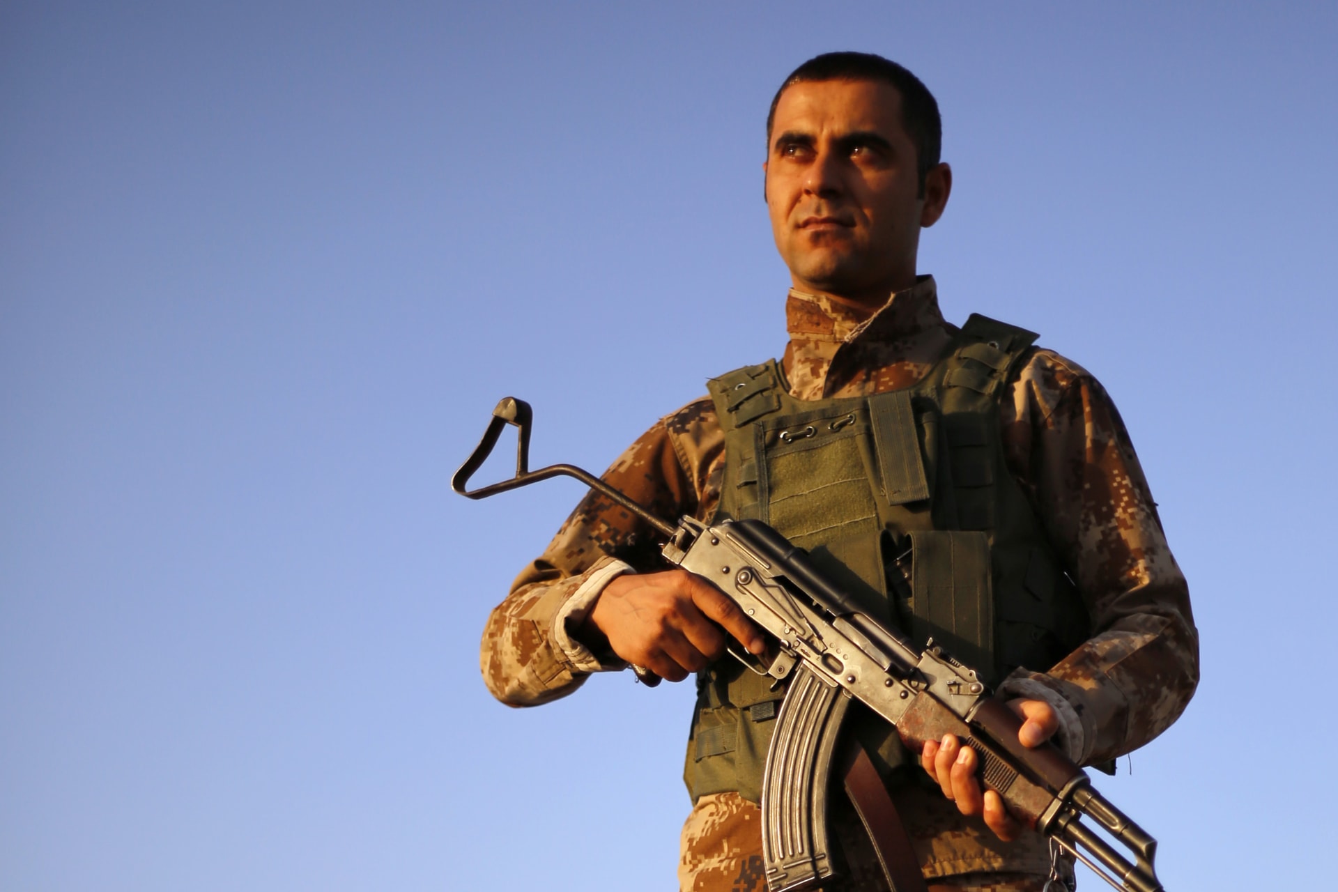 <p>A Kurdish Peshmerga fighter keeps guard as his colleagues train before deploying to fight the Islamic State, at a temporary military camp near the front line in Gwar, northern Iraq, on September 22, 2014.</p>
