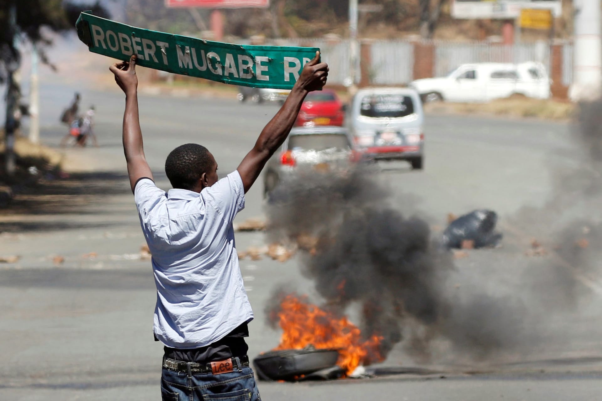 <p>A man carries a street sign as opposition party supporters clash with police in Harare, Zimbabwe, August 26, 2016.</p>
