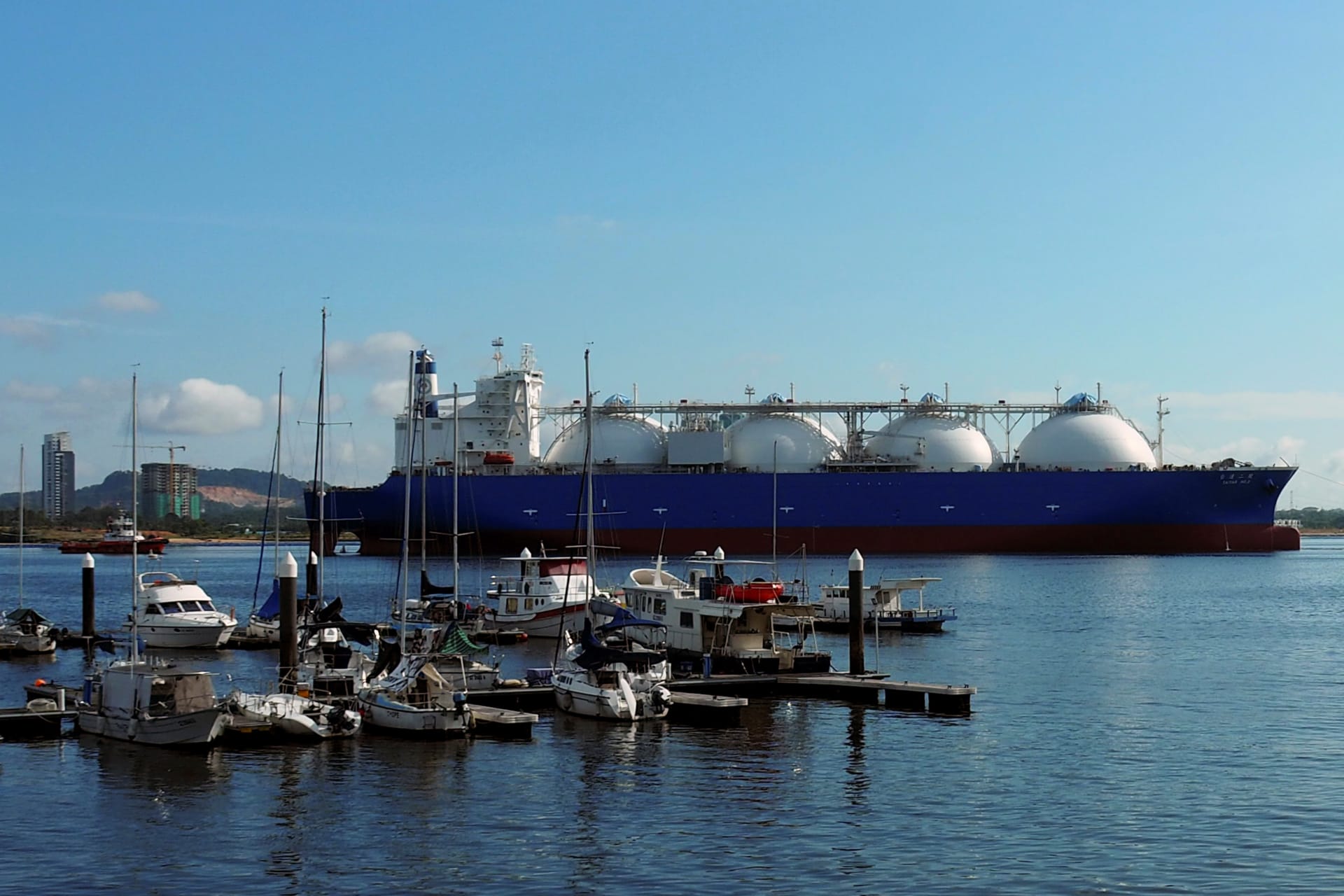 <p>An LNG tanker passes boats along the coast of Singapore on February 3, 2017</p>
