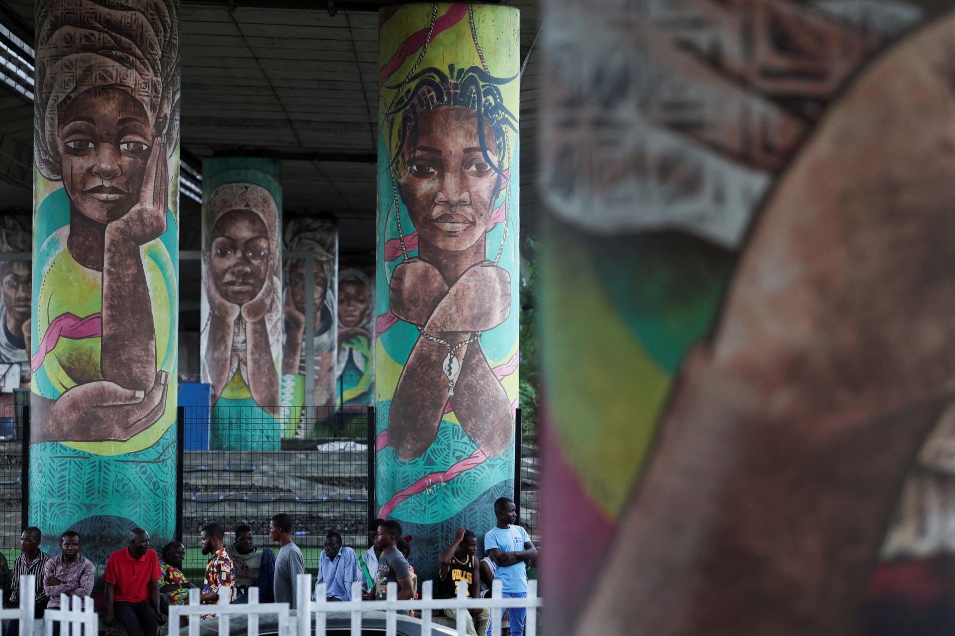 <p>People sit under the Falomo Bridge, where murals depicting the abduction of over two hundred Chibok schoolgirls by Boko Haram are displayed, on the day Nigerians mark the eleventh anniversary of the abduction, in Ikoyi, Lagos, Nigeria, on April 14, 2025.</p>
