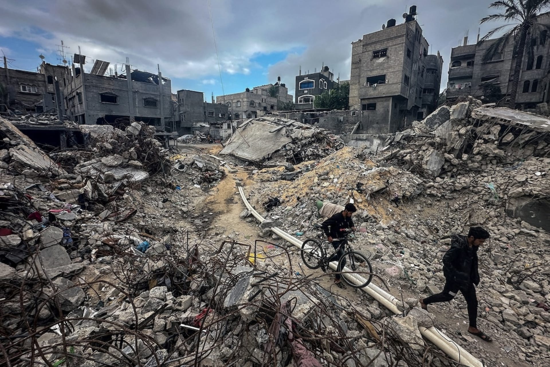 <p>Palestinians walk among the rubble, as they inspect houses destroyed in Israeli strikes at Khan Younis refugee camp in the southern Gaza Strip, November 27, 2023.</p>
