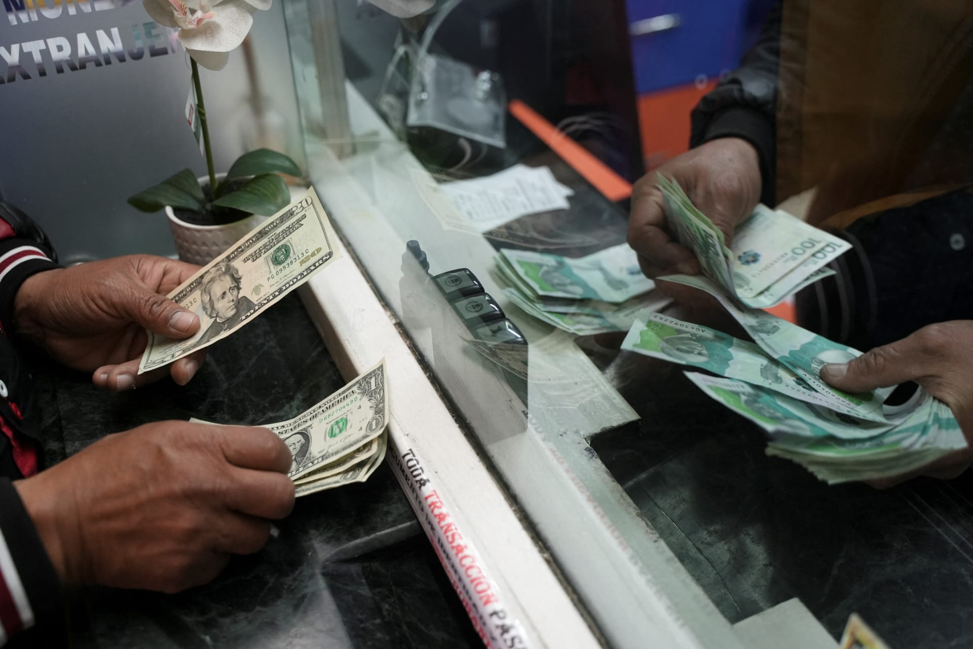 <p>A person exchanges U.S. dollars for Colombian pesos at a currency exchange house in Bogota, Colombia, on June 10.</p>
