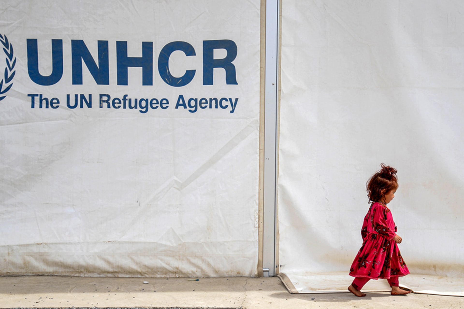 <p>An Afghan refugee girl walks past a registration centre with the United Nations High Commissioner for Refugees (UNHCR) signage, at the Takhta Pul district in Kandahar province on April 7, 2025, upon her arrival from Pakistan.</p>
