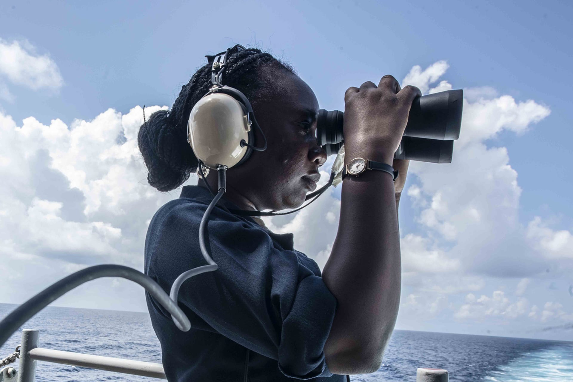 <p>A seawoman uses binoculars while standing aboard the U.S. Navy aircraft carrier USS Ronald Reagan.</p>
