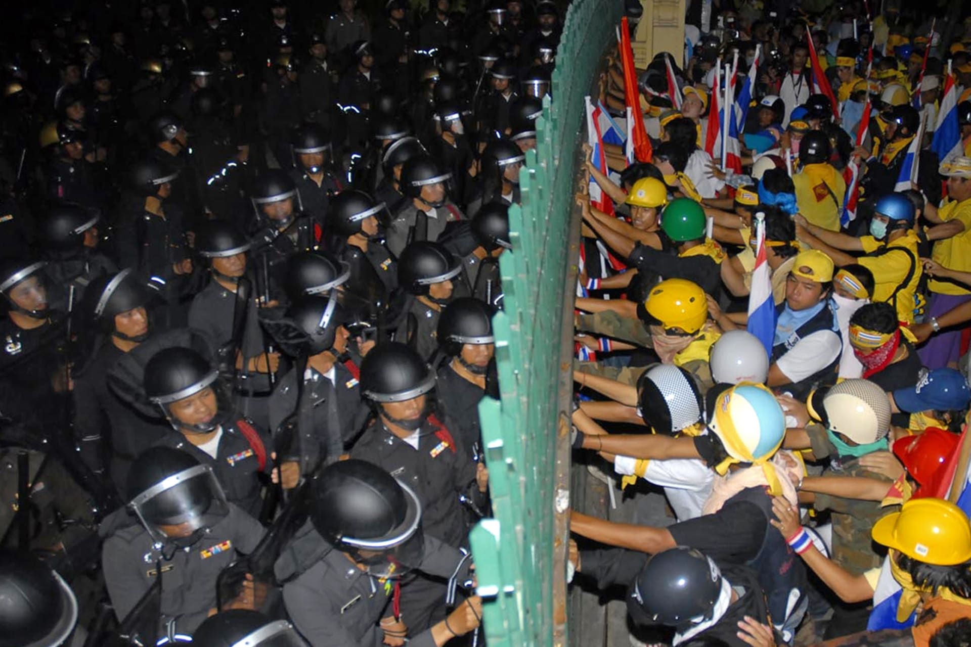 <p>Supporters of the People’s Alliance for Democracy (PAD) push against a gate as police officers stand behind, in Bangkok on August 29, 2008.</p>