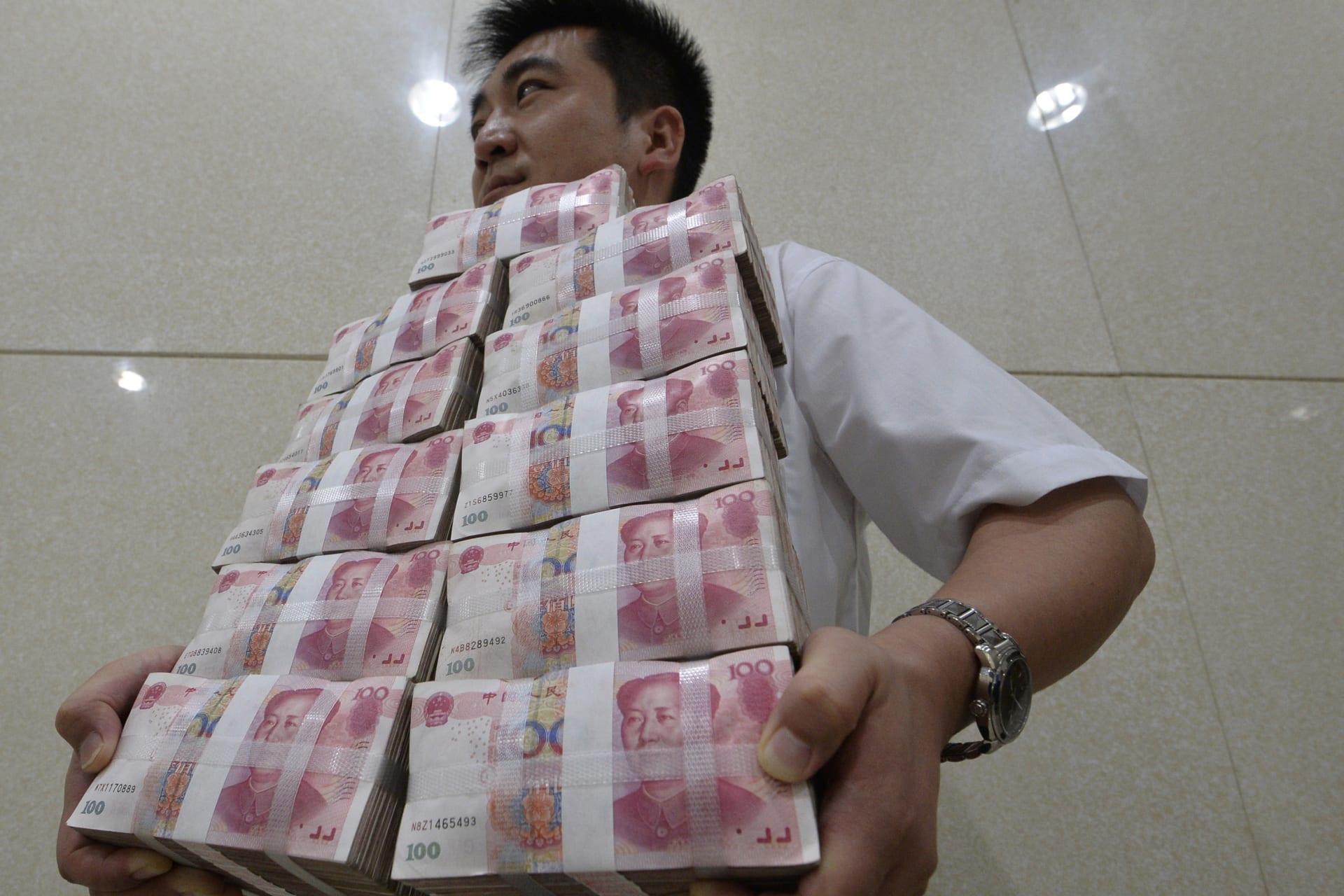 <p>An employee carries bundles of 100 yuan Chinese bank notes to store after counting at a bank in Taiyuan, Shanxi province, on July 4, 2013.</p>
