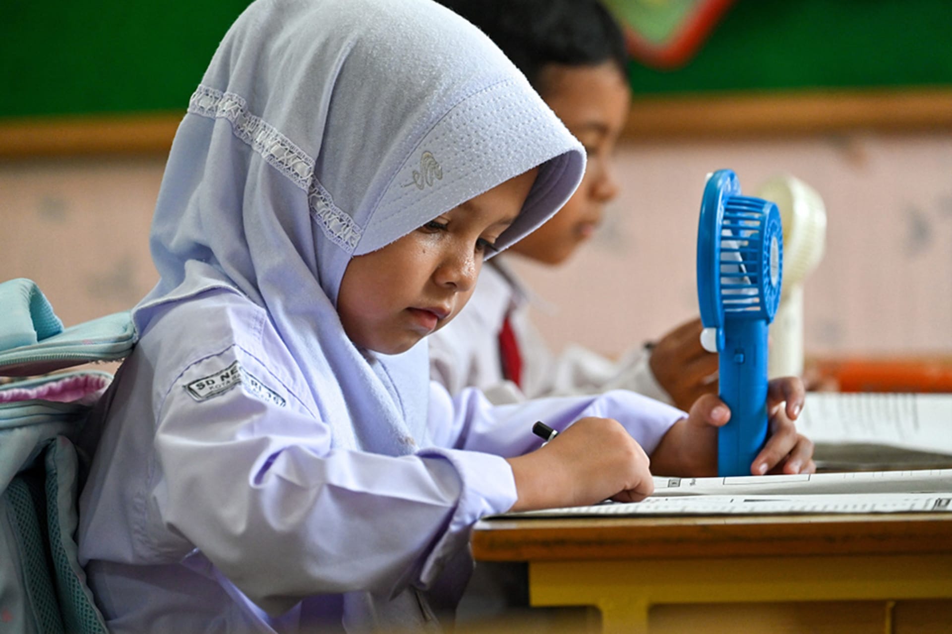 <p>A primary school student uses a portable fan to keep cool in a classroom during hot weather in Banda Aceh</p>
