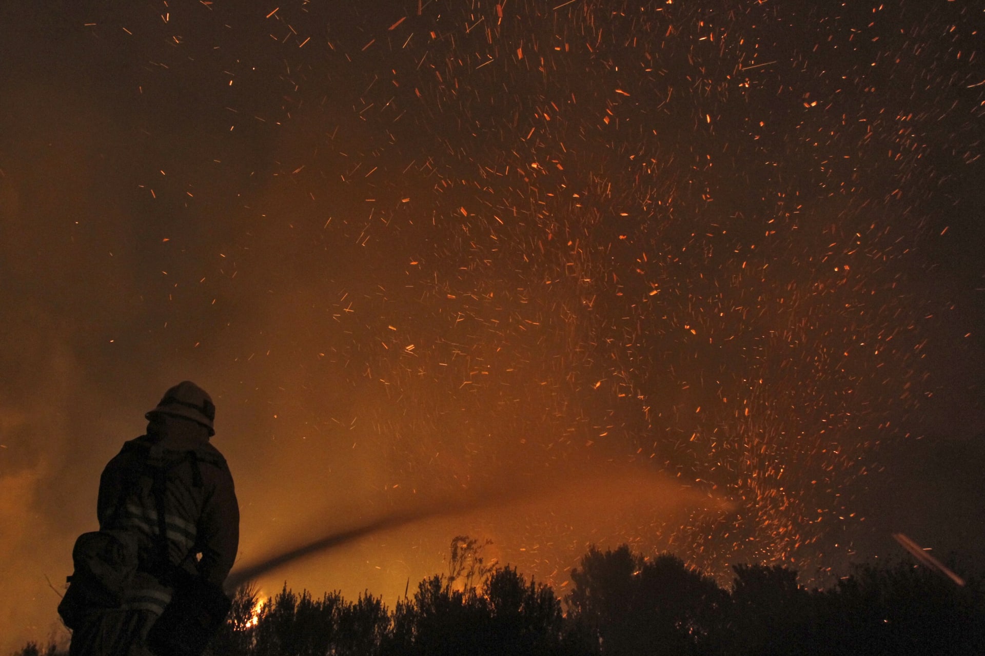 <p>A firefighter douses embers from the Springs Fire at Point Mugu State Park on May 3, 2013.</p>
