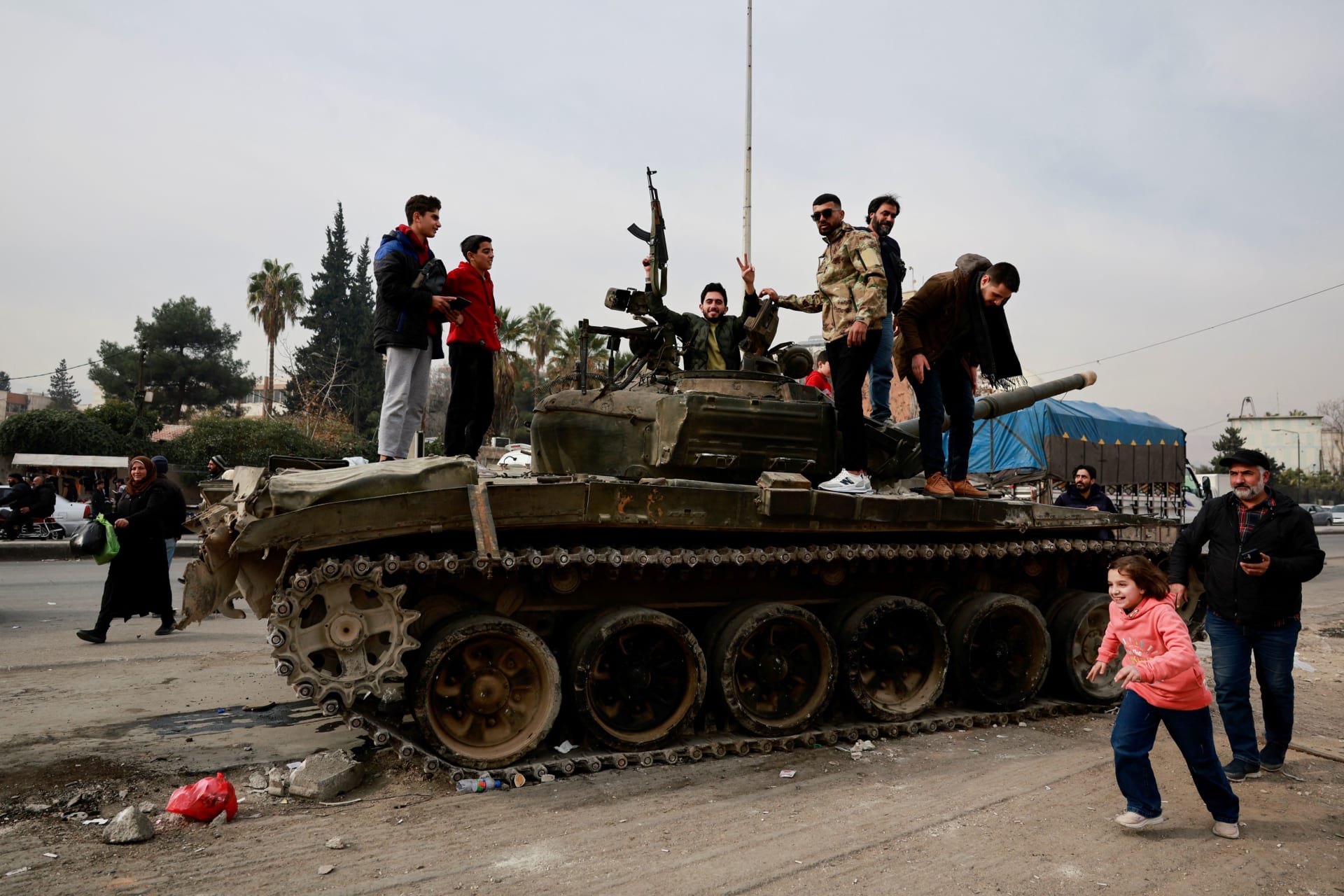 <p>People react as they stand on a tank while celebrating after rebels seized the capital and announced that they have ousted President Bashar al-Assad, in Sednaya, Syria</p>
