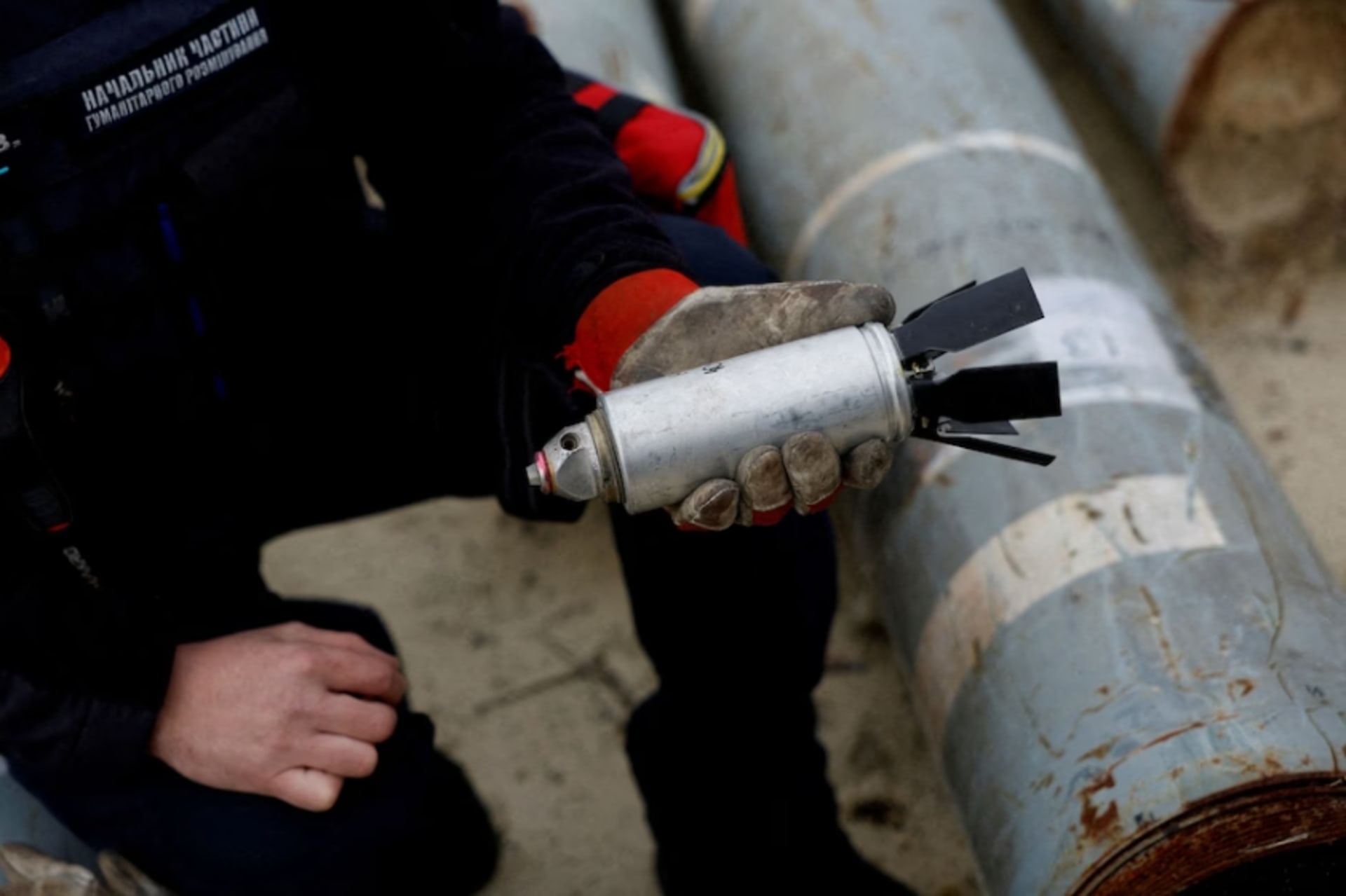 <p>A Ukrainian serviceman holds a defused cluster bomb, among a display of pieces of rockets used by the Russian army, in the Kharkiv region of Ukraine in October 2022.</p>
