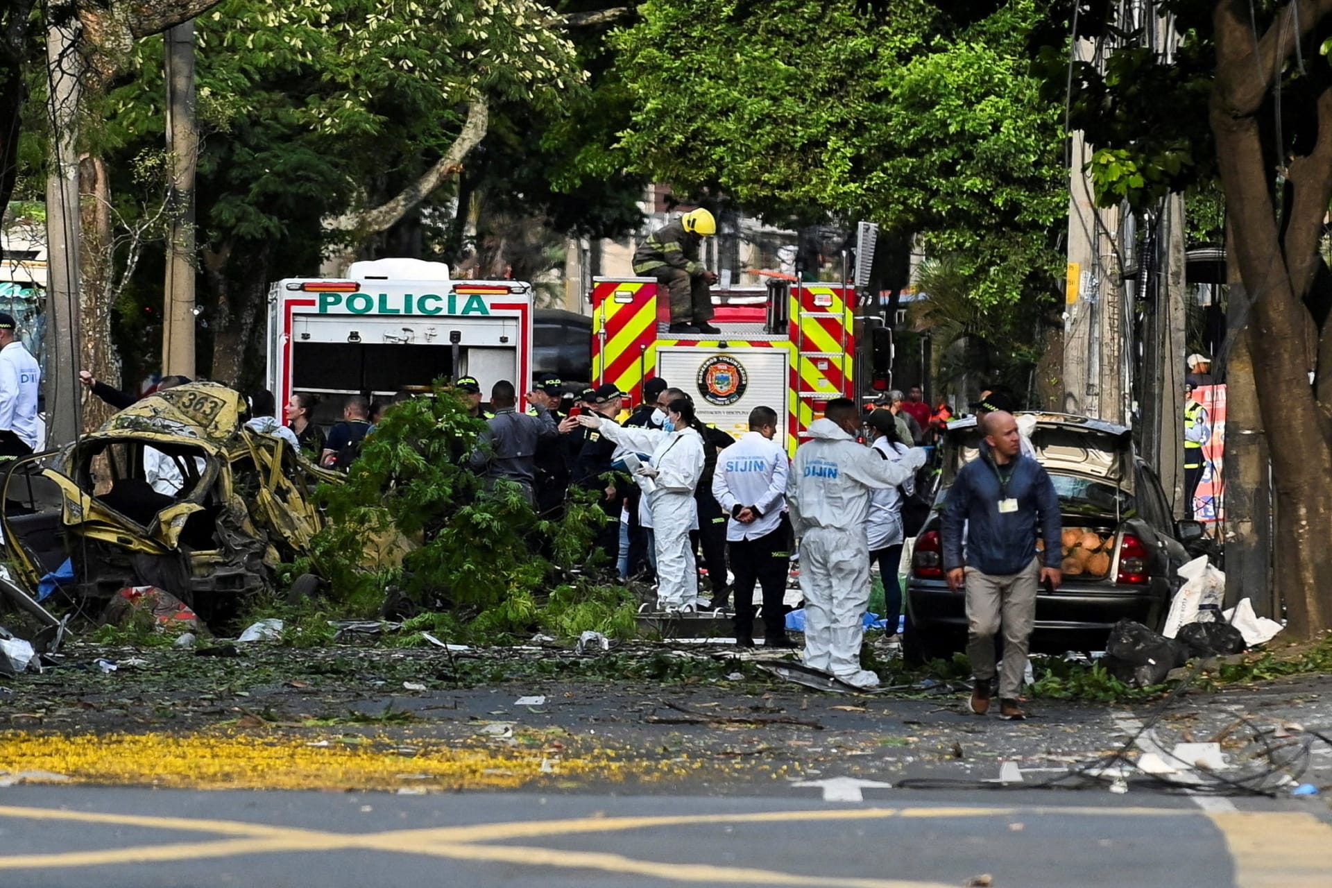 Security forces and forensic team members work near debris following the detonation of a cargo vehicle near a Colombian military base