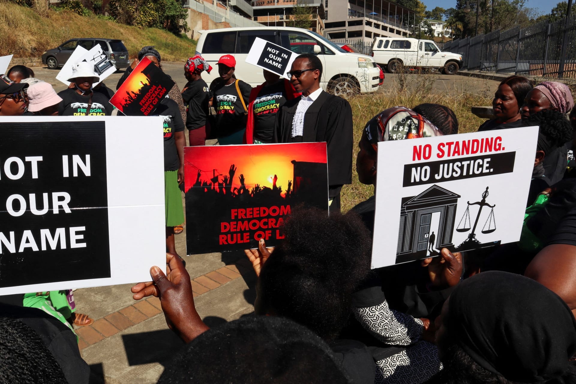 <p>Protesters against an agreement to accept third-country deportees hold placards as lead applicant and lawyer Mzwandile Masuku addresses them outside the court in Mbabane, Eswatini on August 22, 2025.</p>
