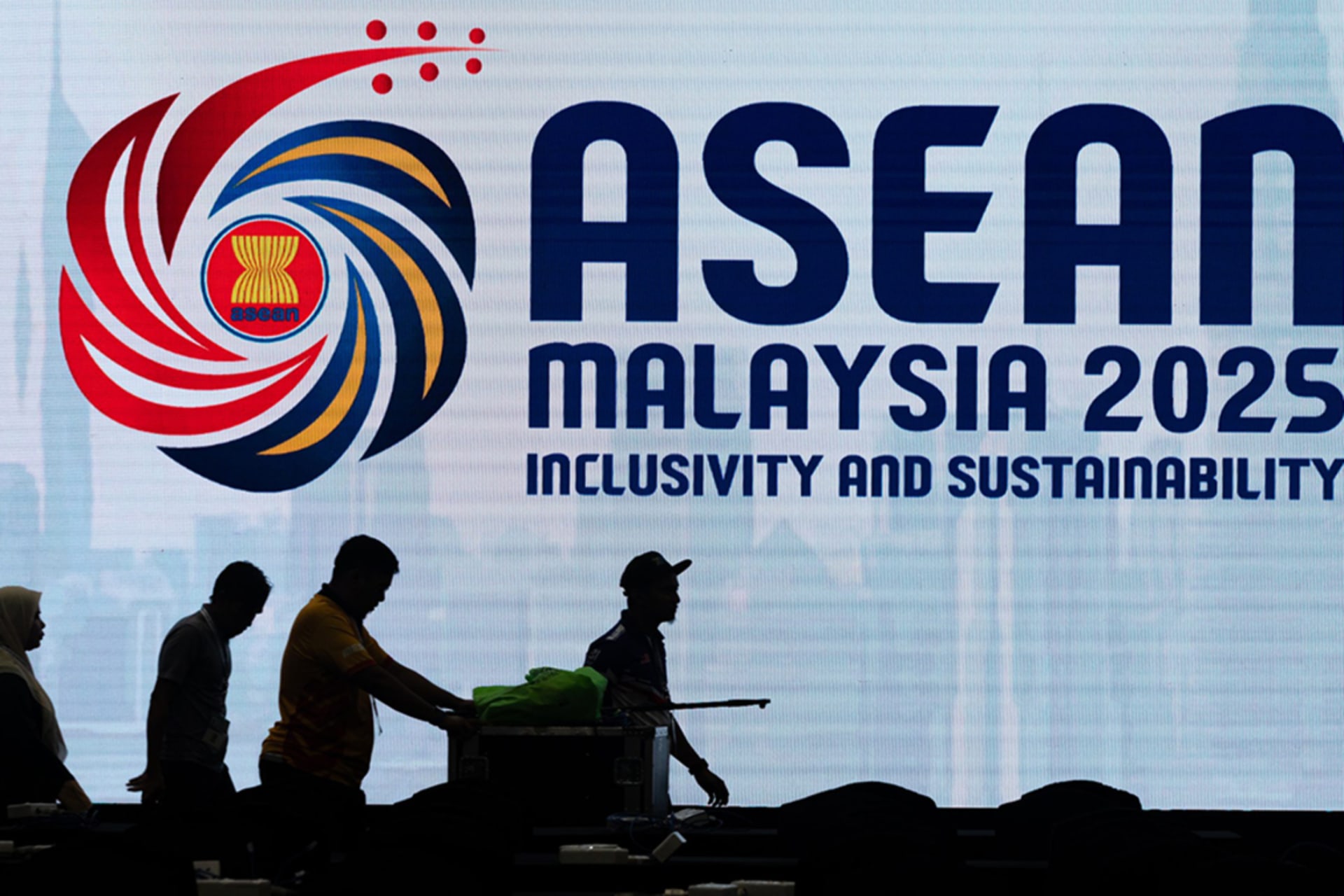 <p>Workers walk past an electronic an ASEAN banner in Kuala Lumpur, Malaysia.</p>
