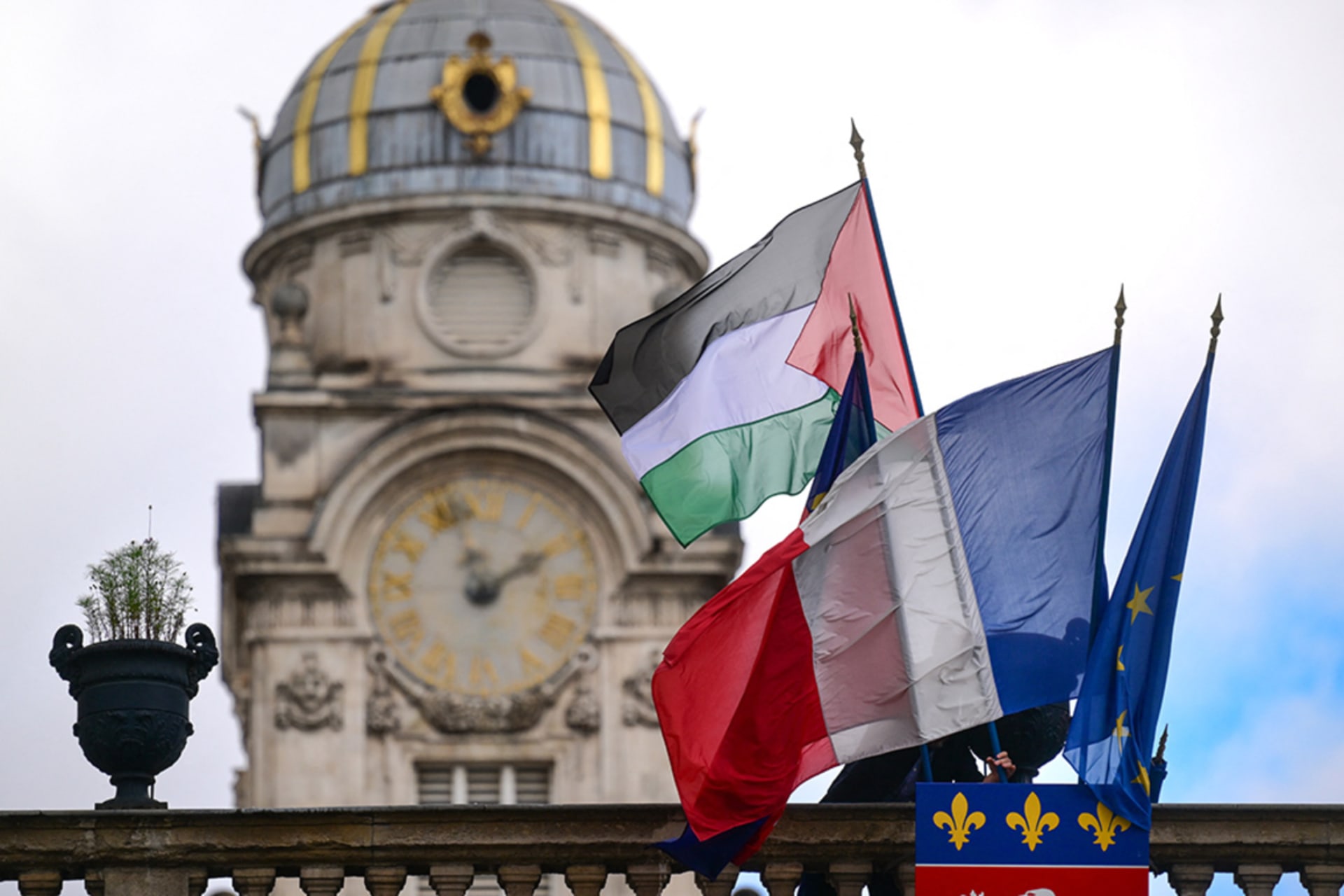 <p>An employee places the Palestinian flag along side the French Flag, flag of Lyon, and the European Union flag, over the entrance of the Lyon City Hall, on the day France plans the recognition of a Palestinian State at the United Nations, September 22.</p>
