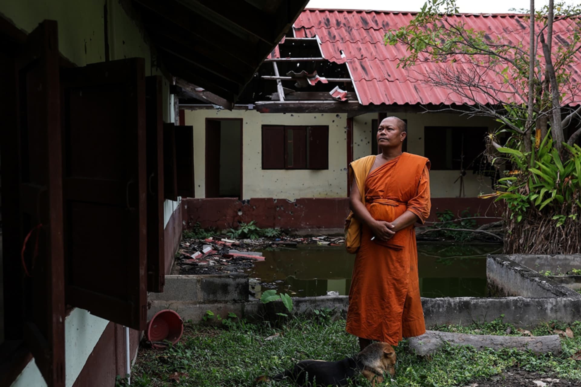 <p>A monk stands near a damaged dorm at Thai Niyom temple, which was hit by Cambodian artillery during the Thailand-Cambodia border conflict in Surin Province, Thailand on November 3.</p>
