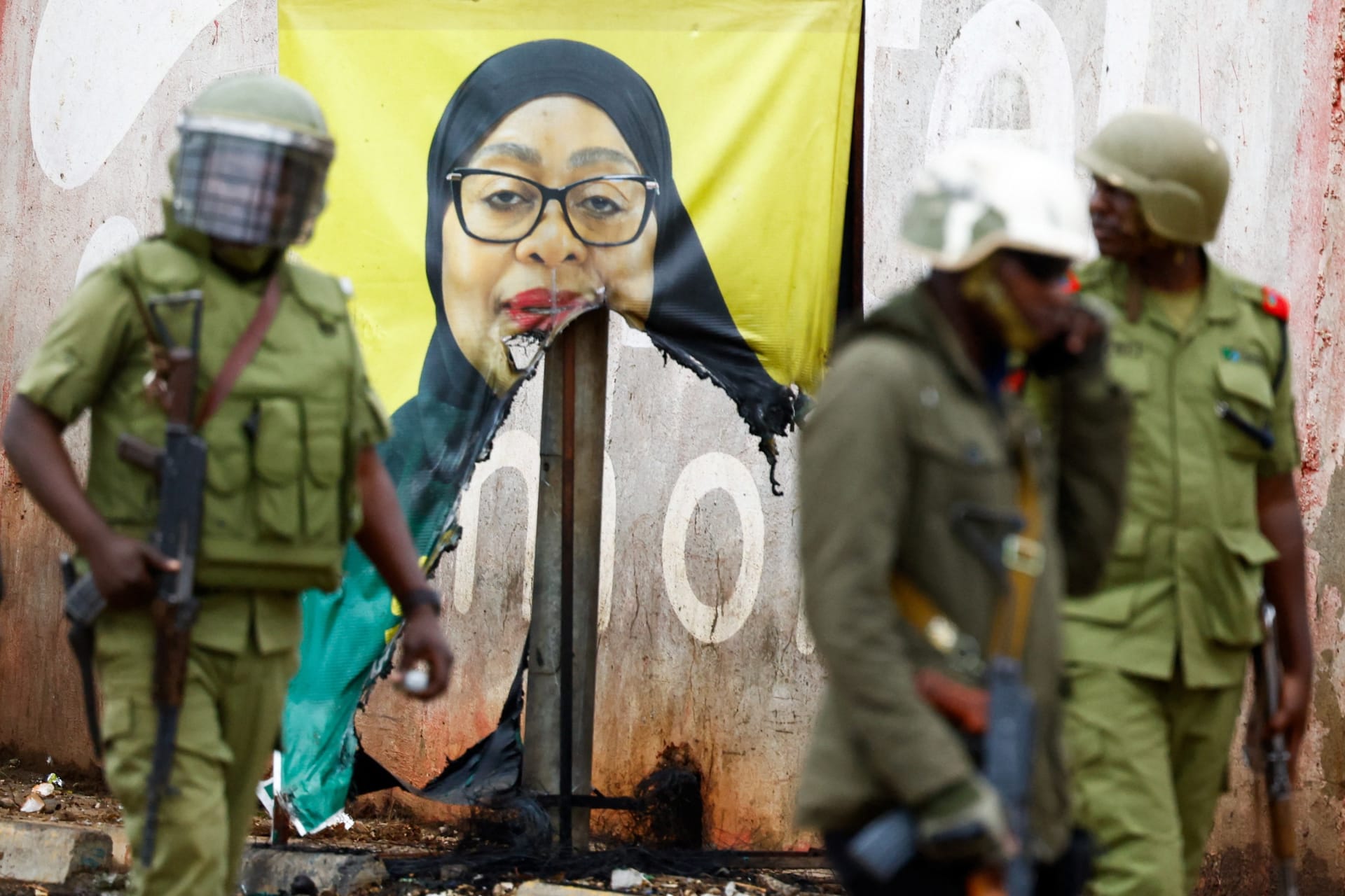 <p>A Tanzanian riot police officer walks past a vandalized campaign poster of President Samia Suluhu Hassan at the Namanga One-Post Border crossing point between Kenya and Tanzania on October 30, 2025.</p>
