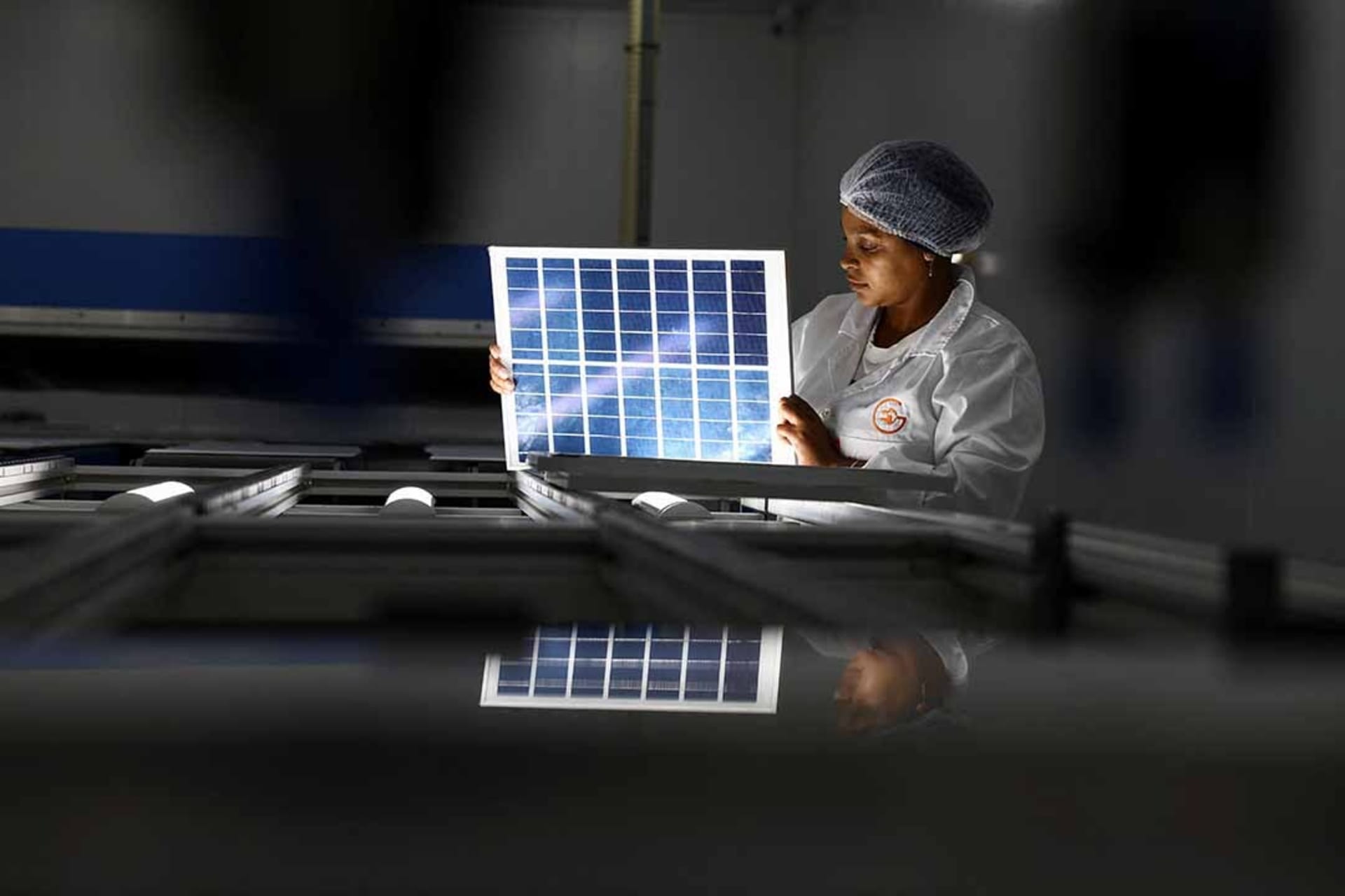 <p>A woman looks over a solar panel at an women-run solar panel factory in Cape Town, South Africa.</p>
