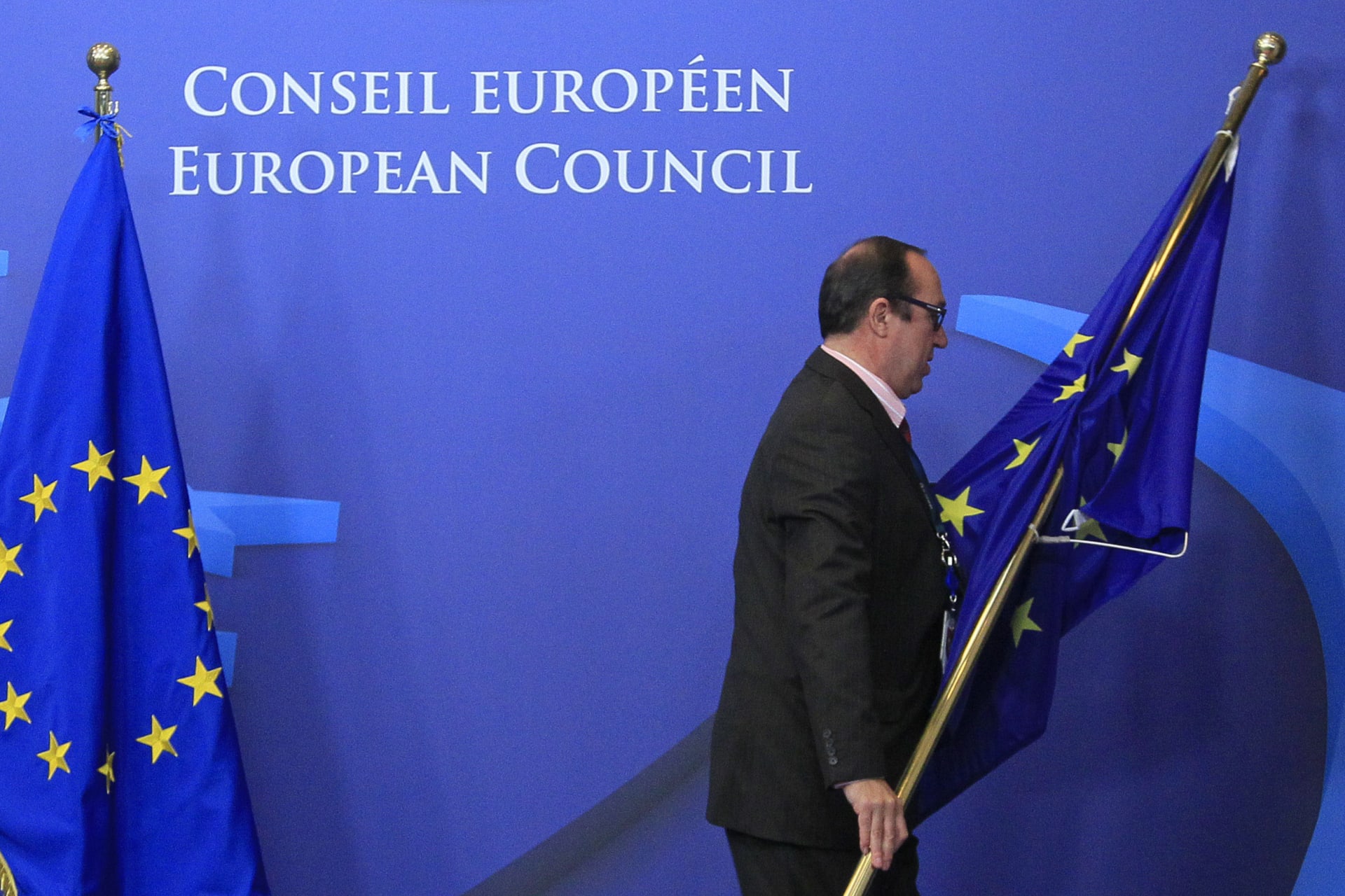 <p>An employee at the EU council adjusts European Union flags at the entrance of the council headquarters for an European Union leaders summit discussing the European Union’s long-term budget in Brussels on November 22, 2012.</p>
