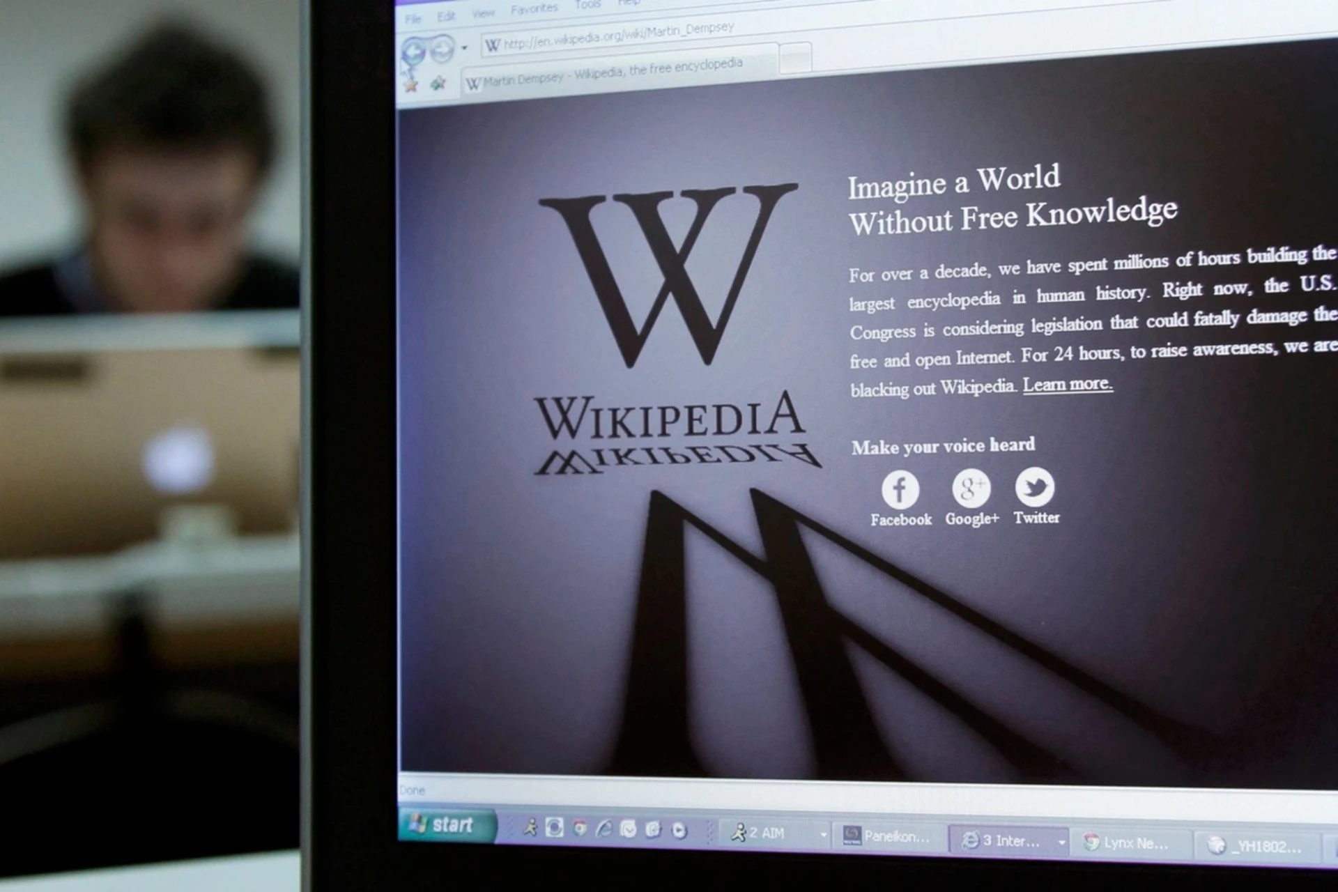 A reporter's laptop shows the Wikipedia blacked out opening page.