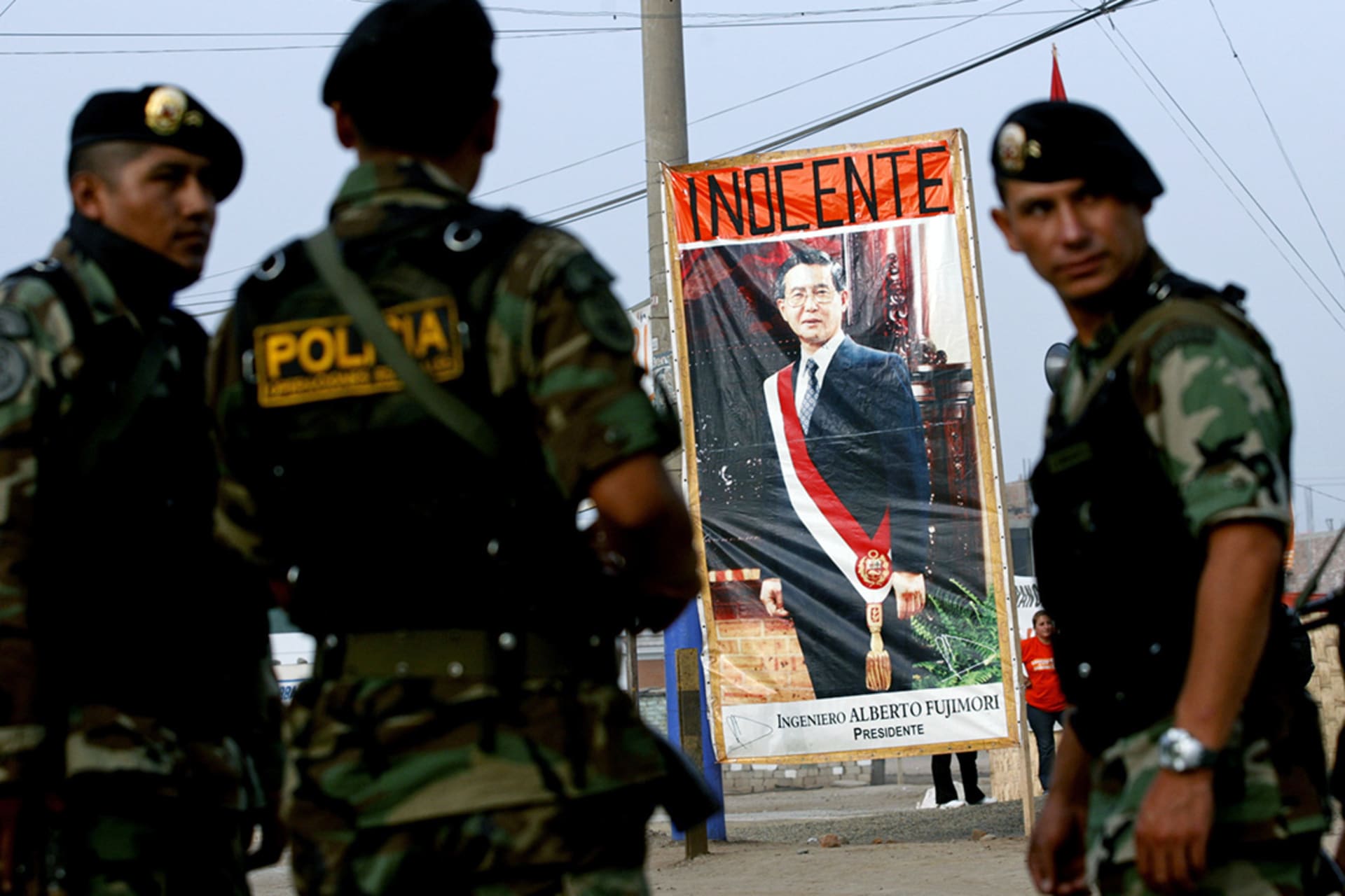 Police stand next to a poster of former Peruvian President Alberto Fujimori at the Special Police Headquarters in Lima before his trial begins. 
