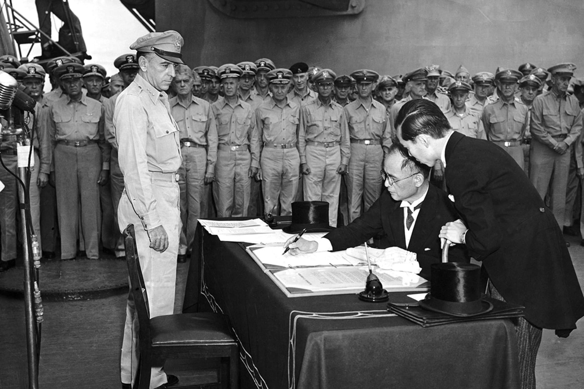 Japanese delegates sign the formal surrender on behalf of the imperial Japanese government onboard the USS Missouri in Tokyo Bay.
