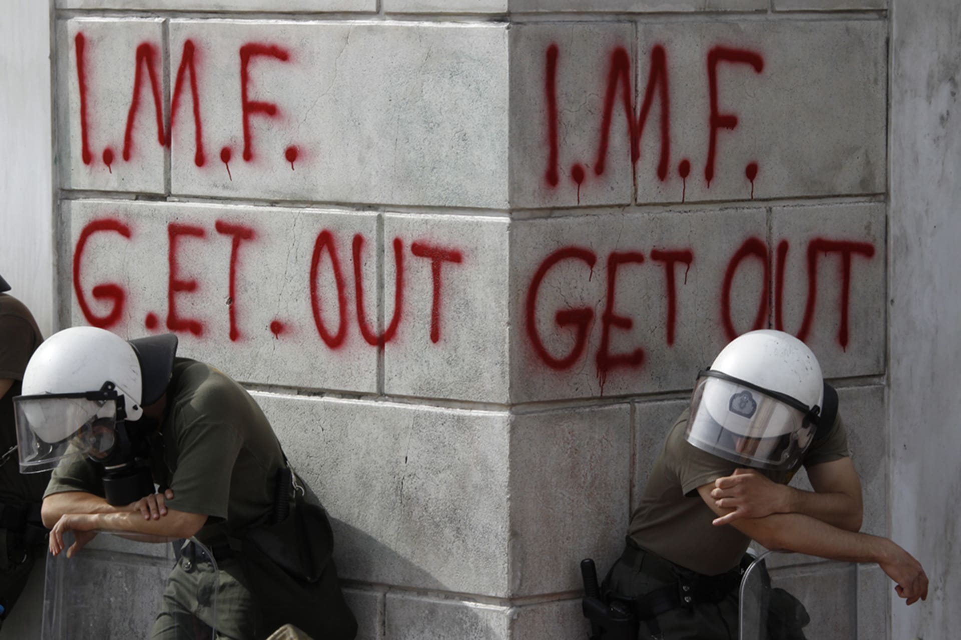 Greek riot policemen rest in front of graffiti written on the wall of a bank in Athens during violent demonstrations over austerity measures demanded by the May 2, 2010, EU-IMF bailout. 

