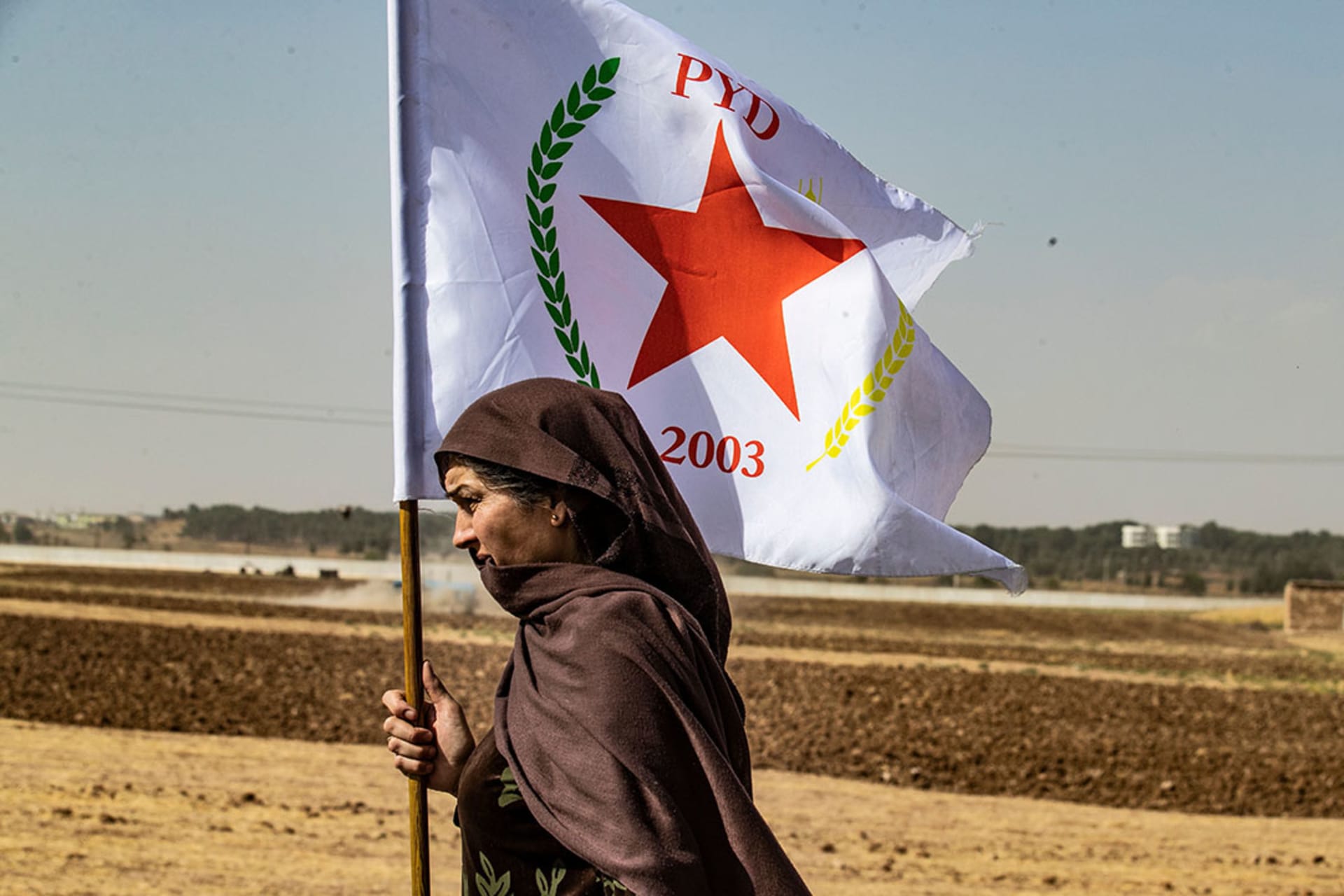 A Syrian Kurdish woman carries the flag of the Kurdish Democratic Union Party (PYD). 