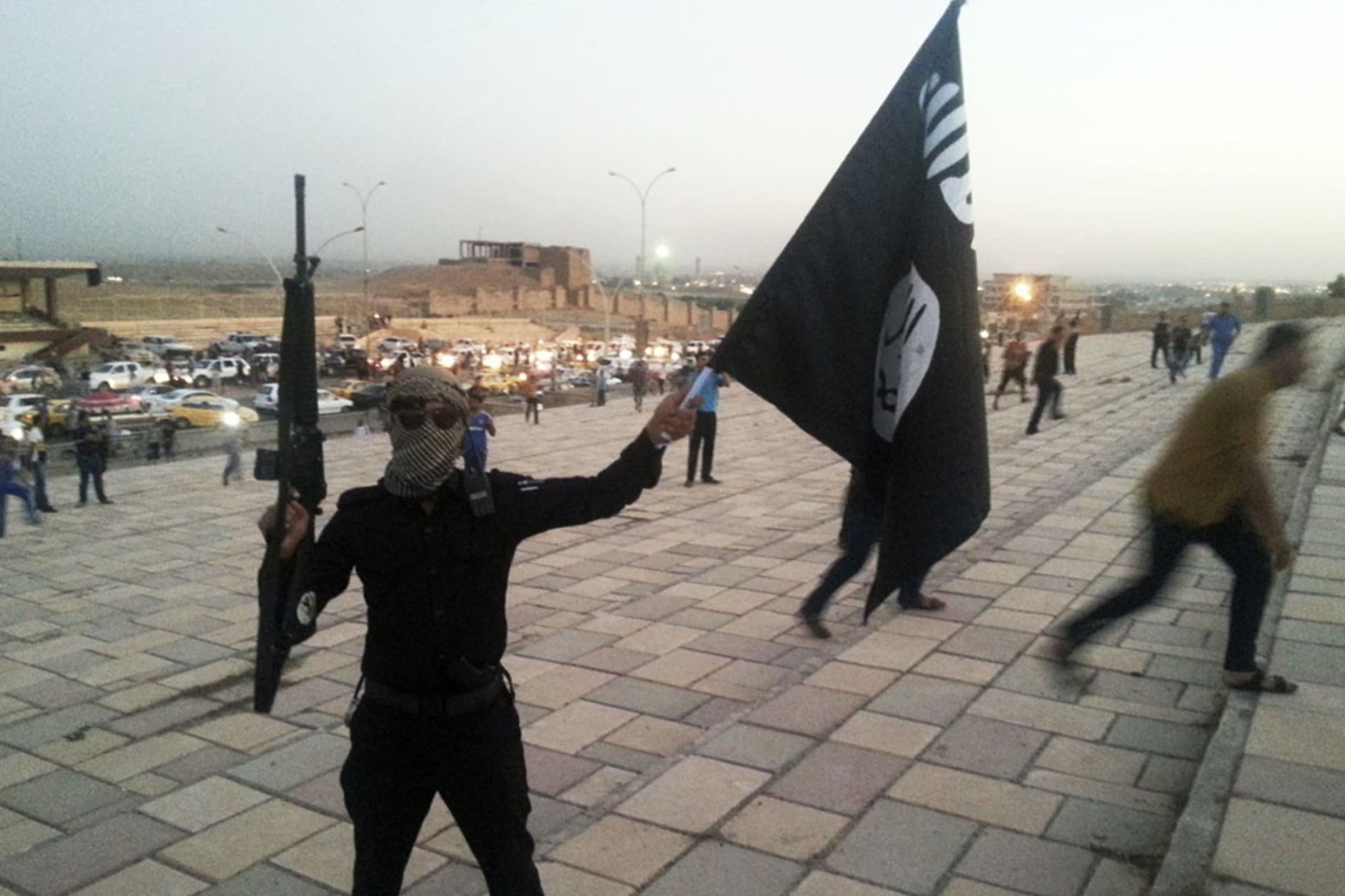 An Islamic State fighter holds a flag bearing the group’s symbol on the streets of Mosul, Iraq, on June 23, 2014.

